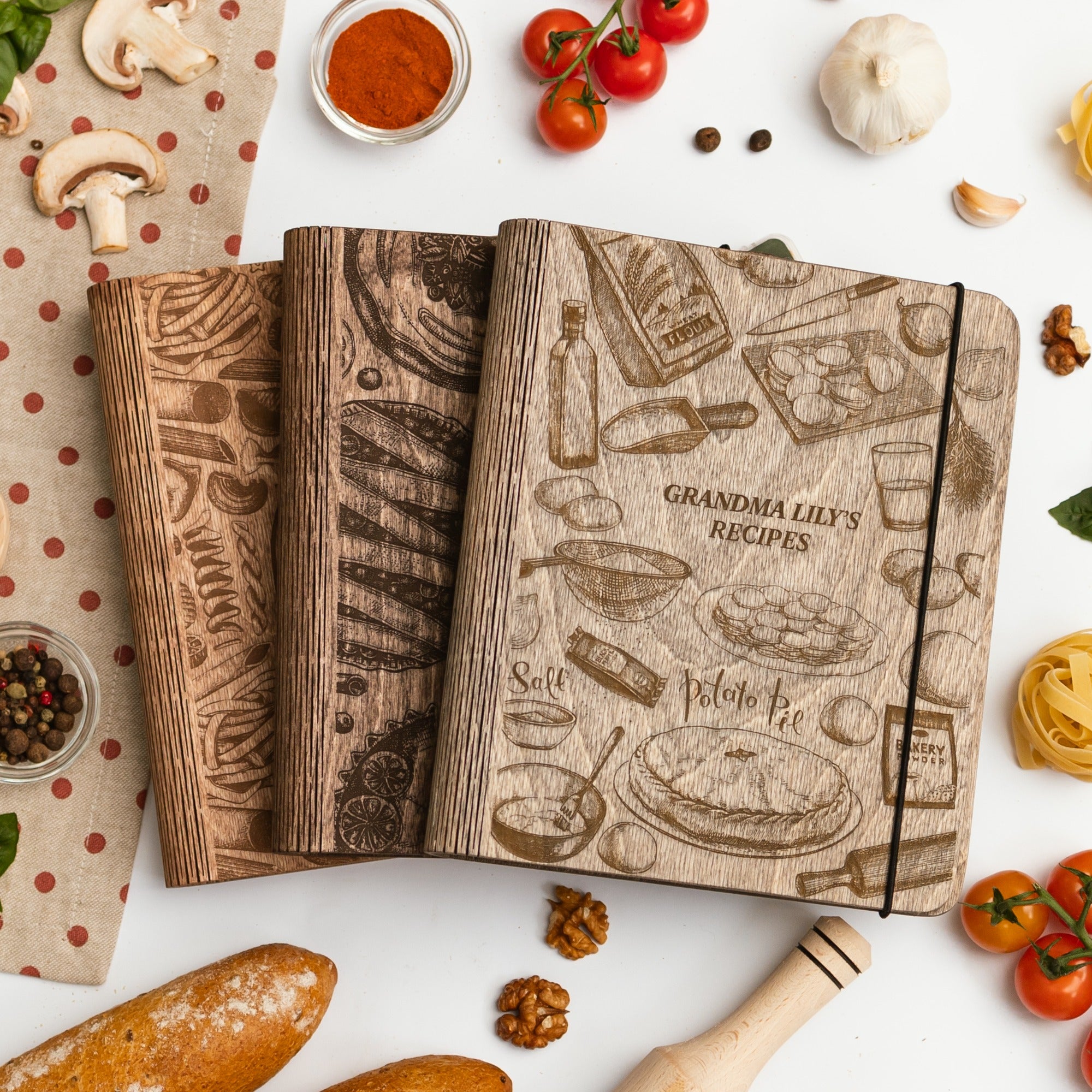 Wooden-look recipe notebook with food illustrations on a white surface with kitchen items.