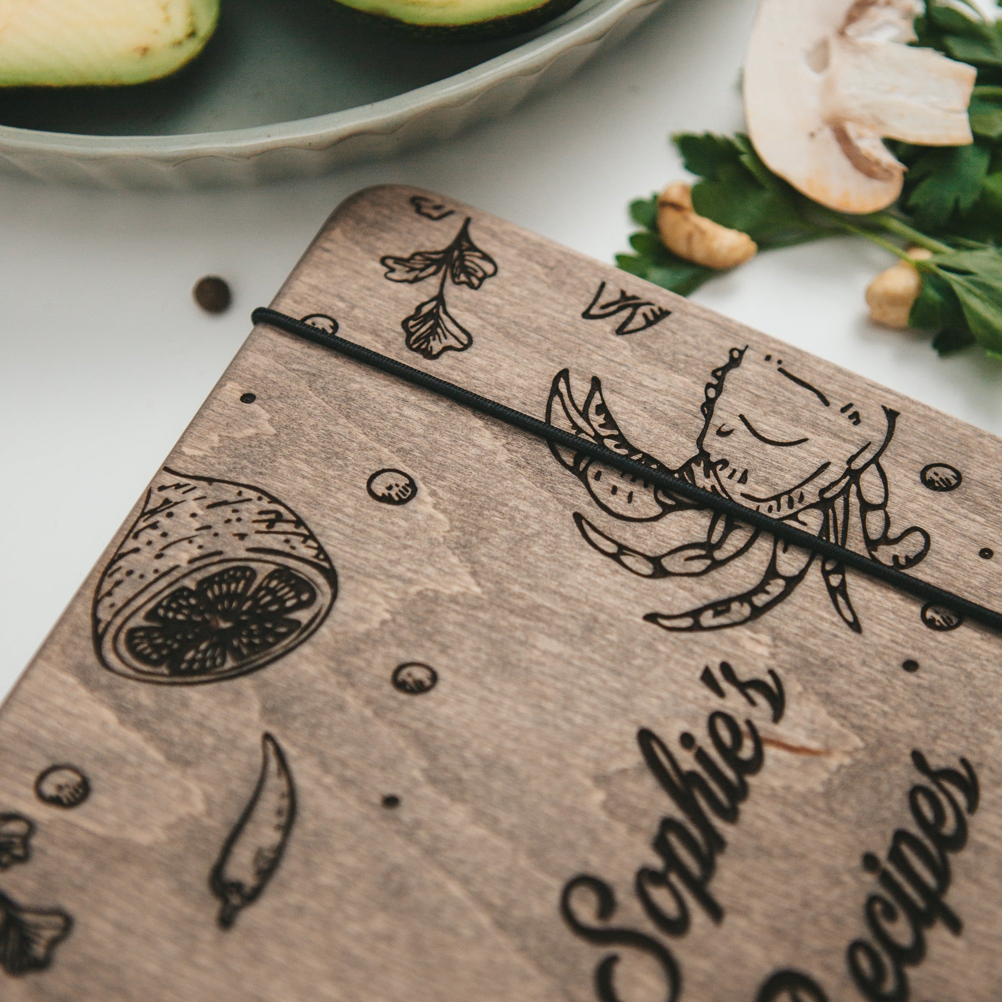 Wooden notebook with engraved illustrations and text on a table with ingredients
