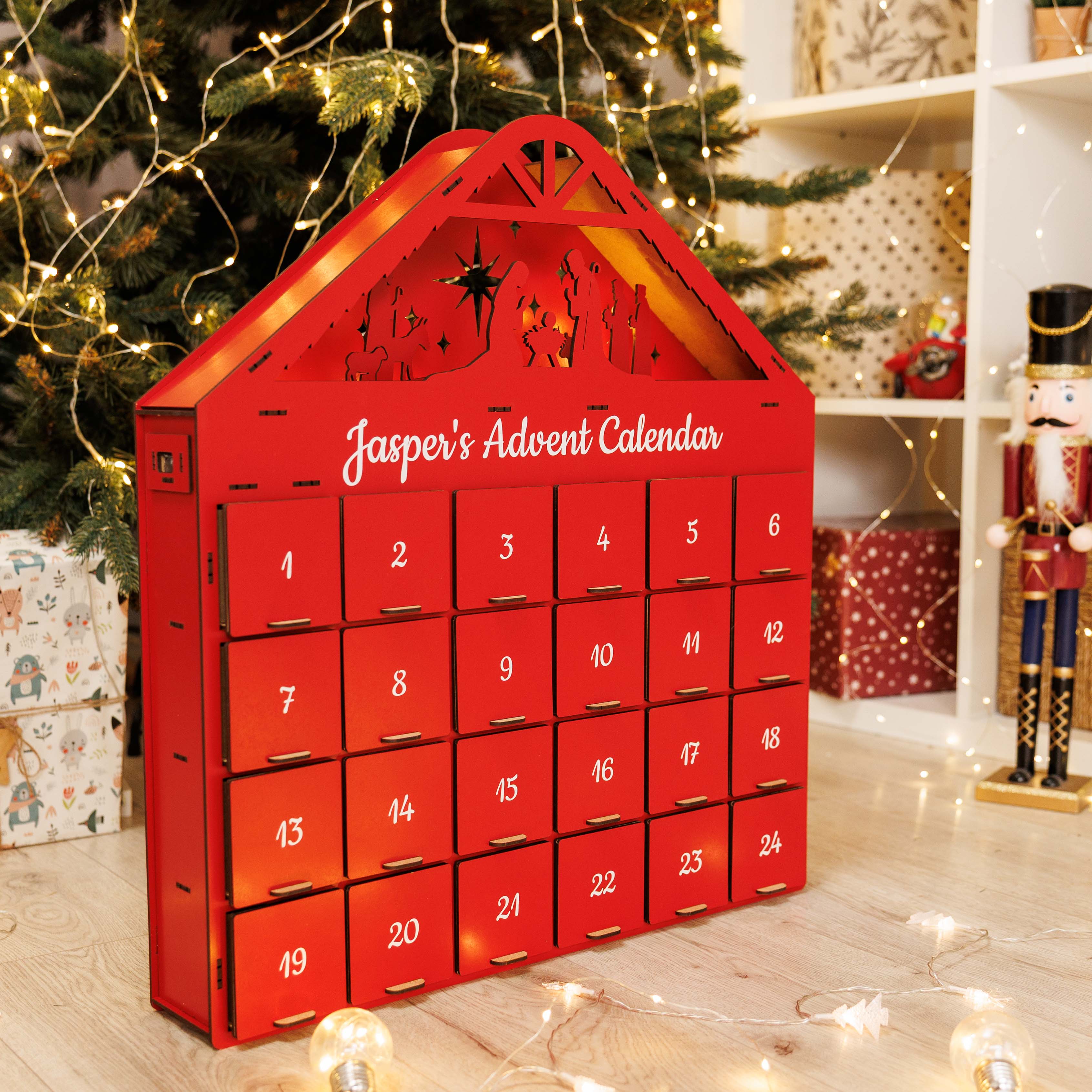 Red advent calendar with 'Jasper's Advent Calendar' text, Christmas tree and decorations in the background.
