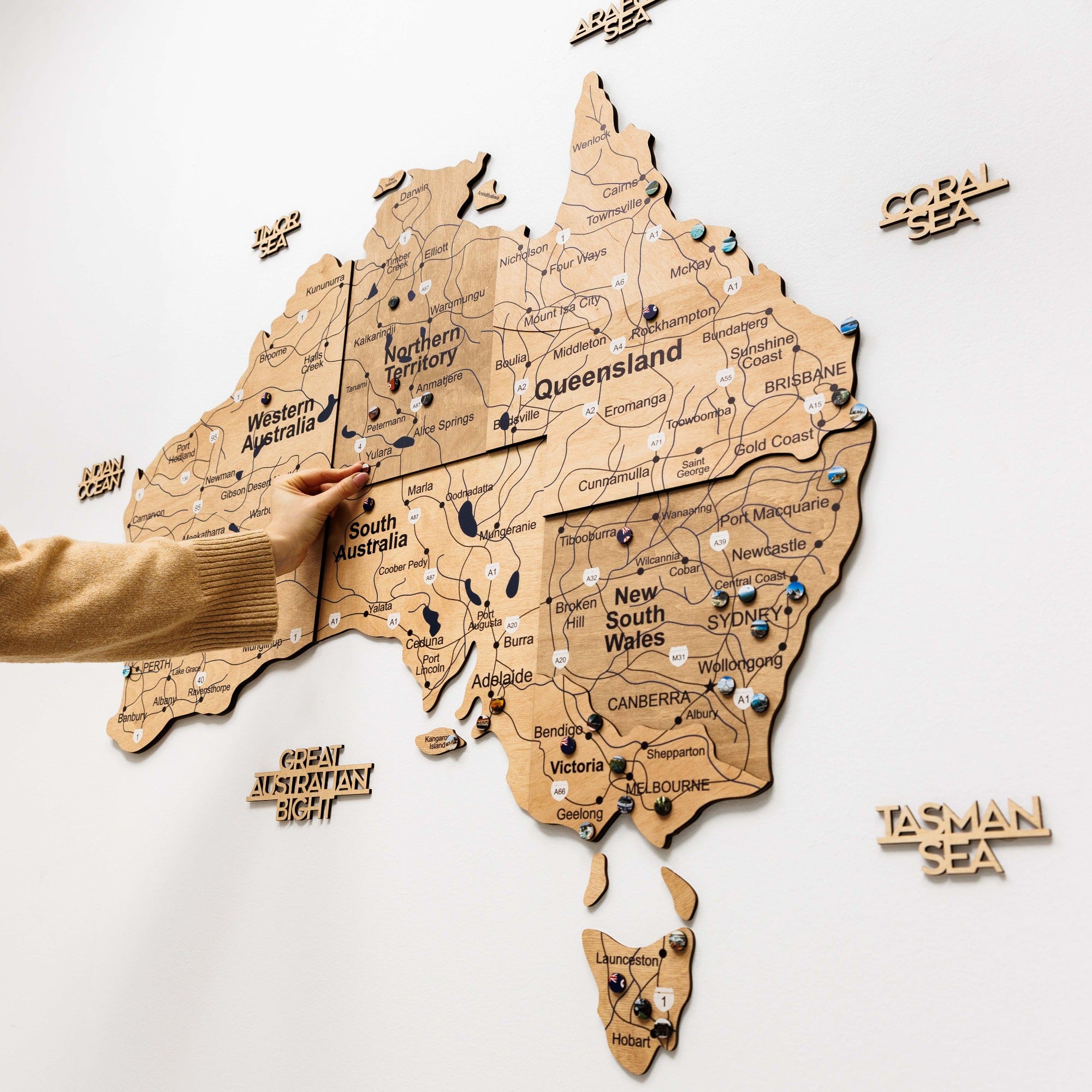Wooden map of Australia with pins on a white background