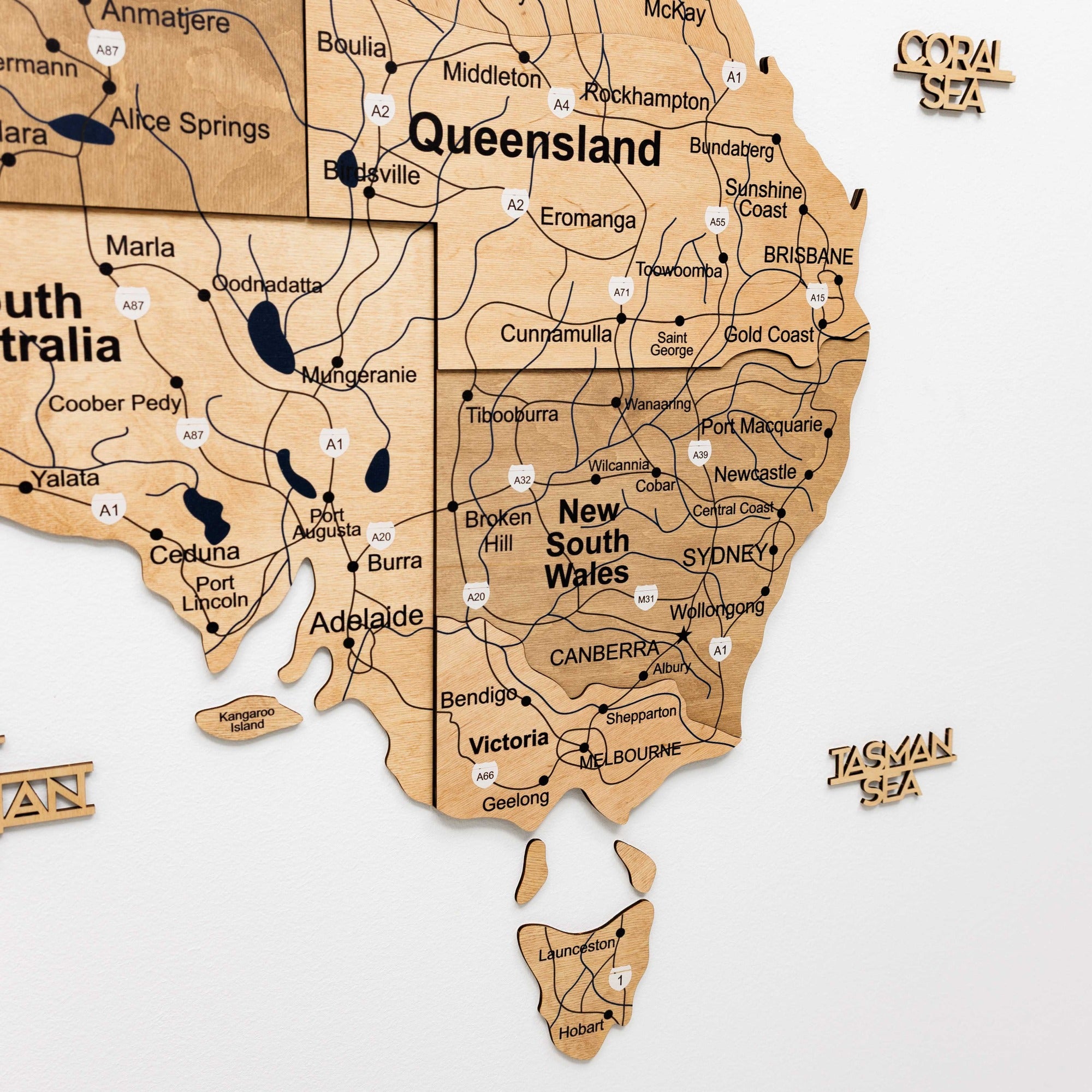 Wooden map of Australia with labeled states on a white background