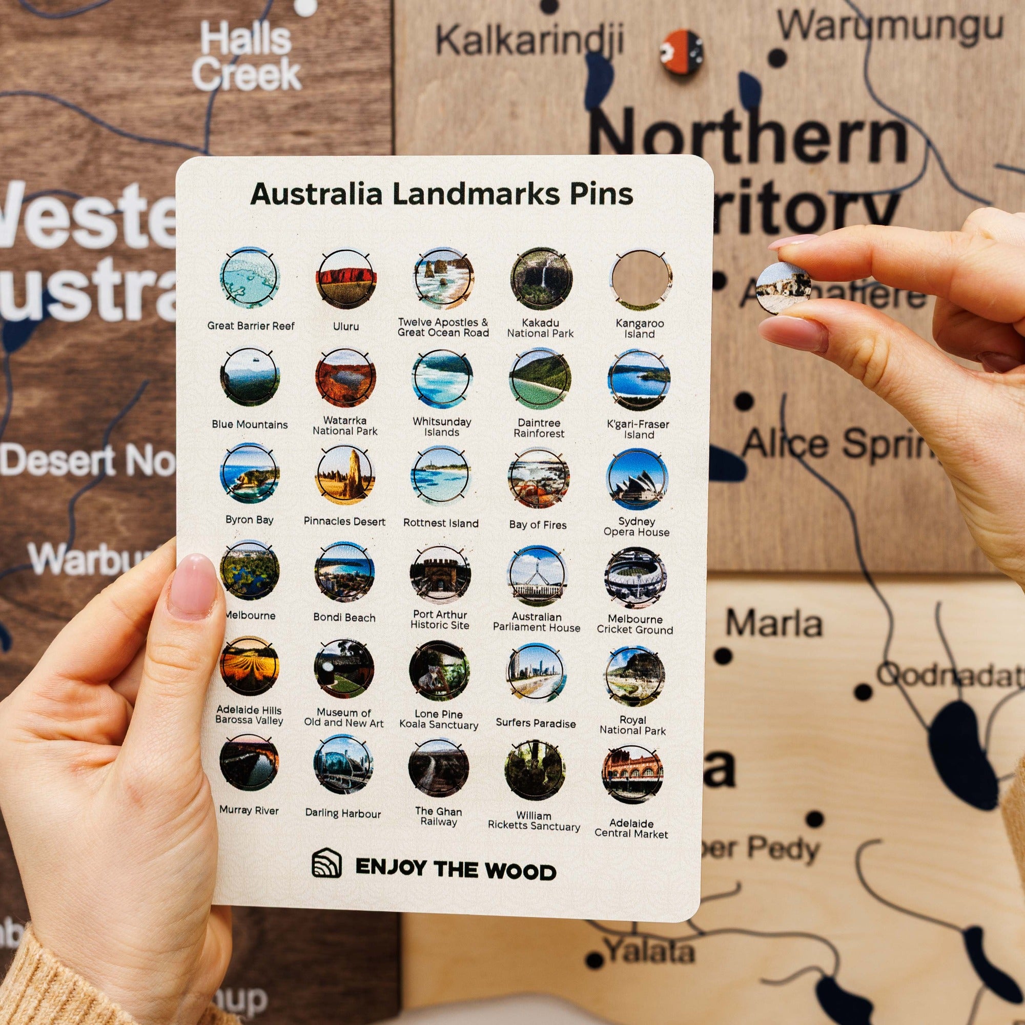 Card with Australia Landmarks Pins held by a hand against a map background