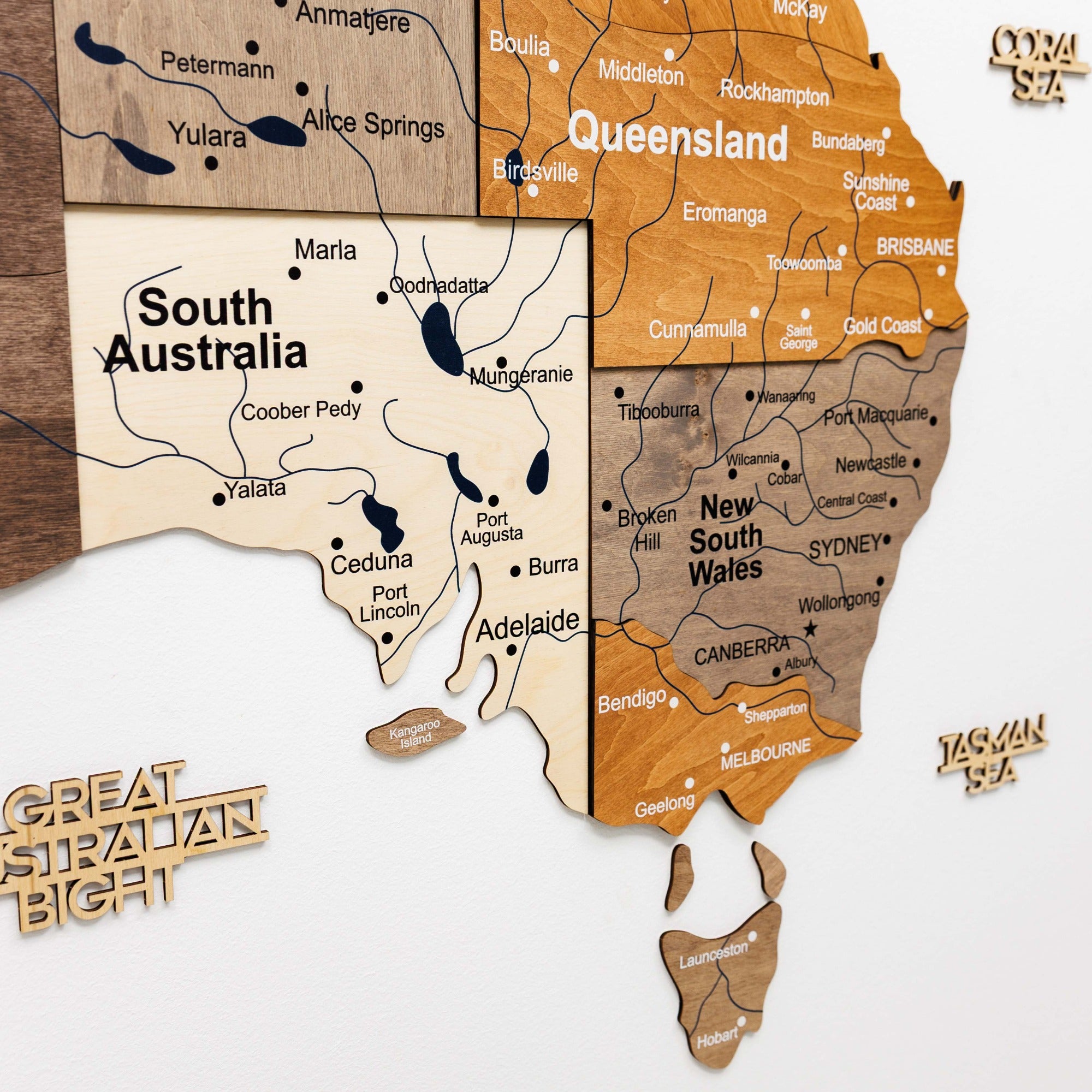 Wooden map of Australia with labeled states on a white background