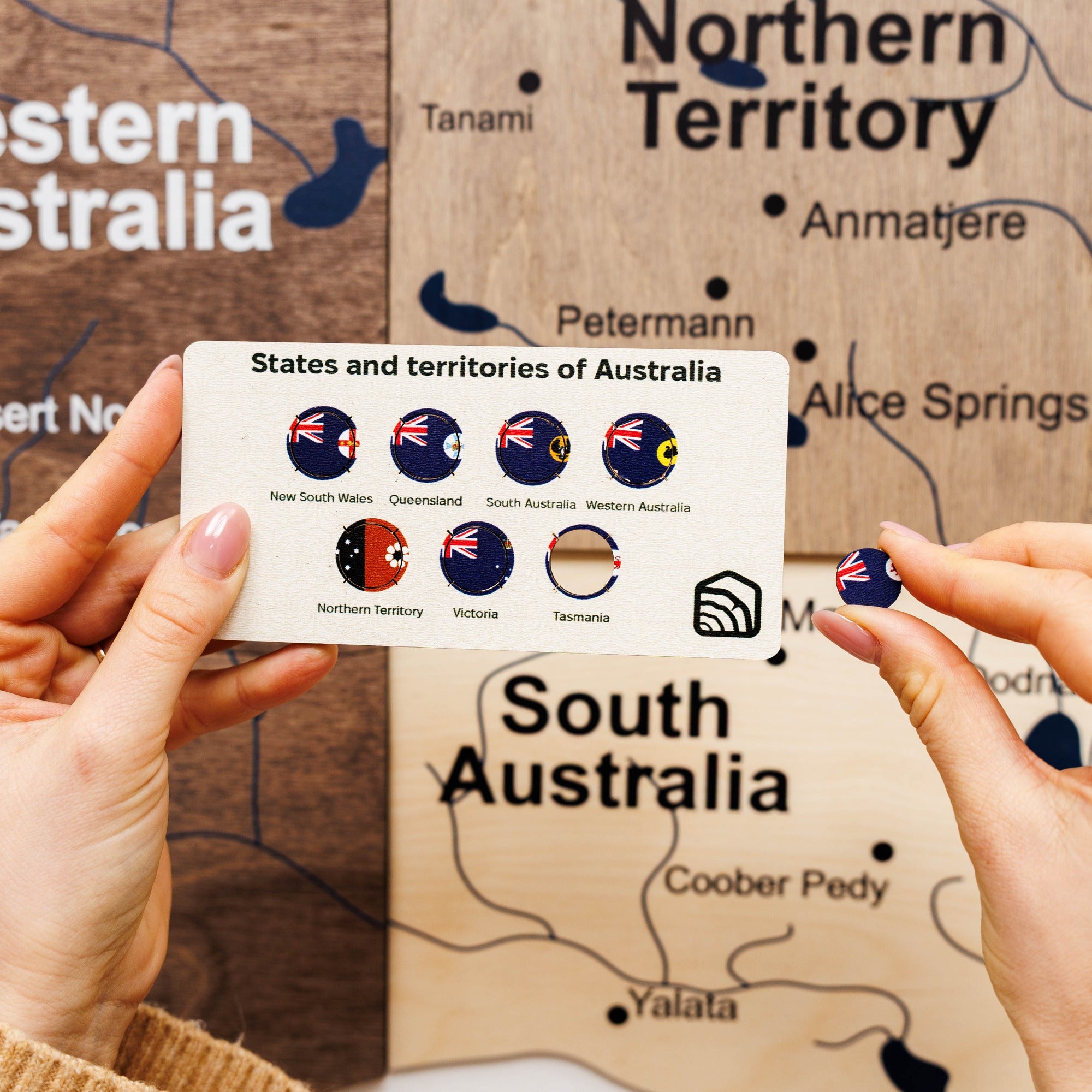 Card with icons of Australia's states and territories held over a map of Australia.