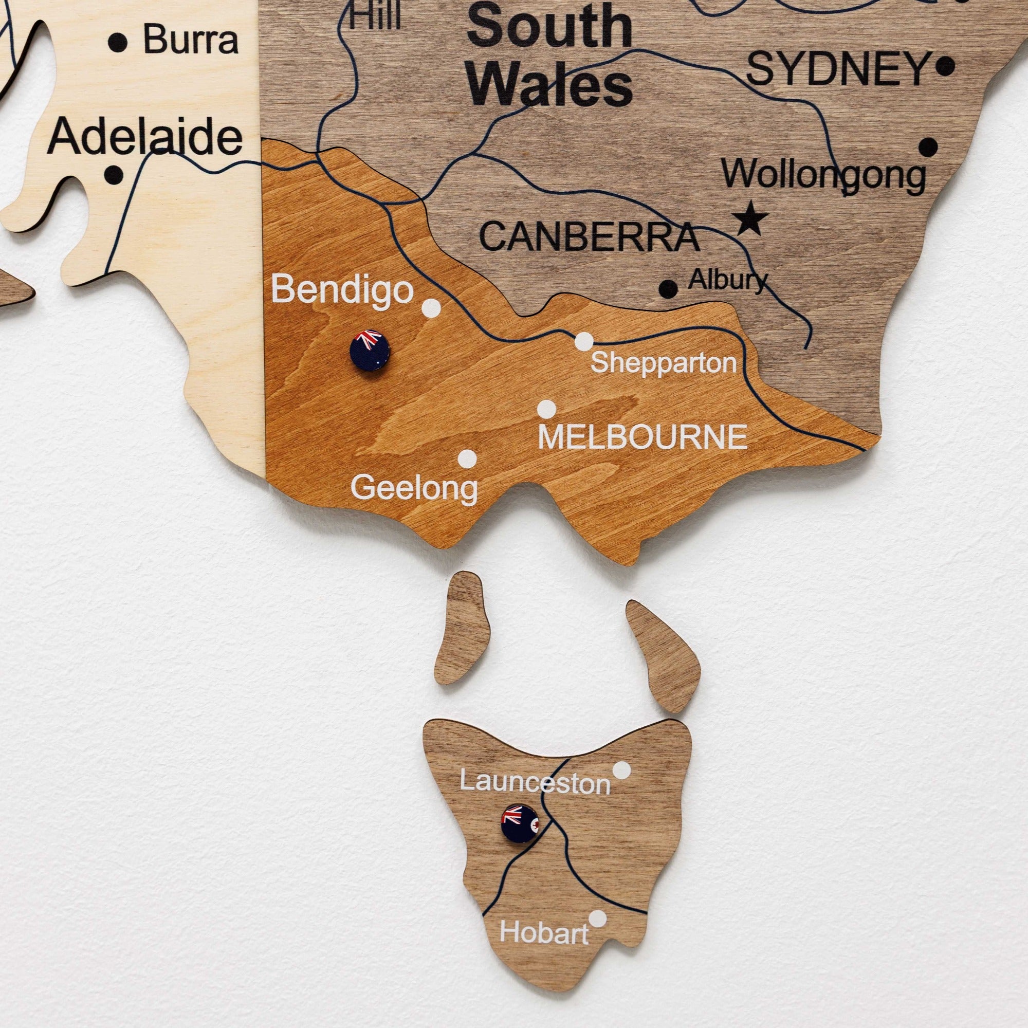 Wooden map of Australia with cities labeled on a white background