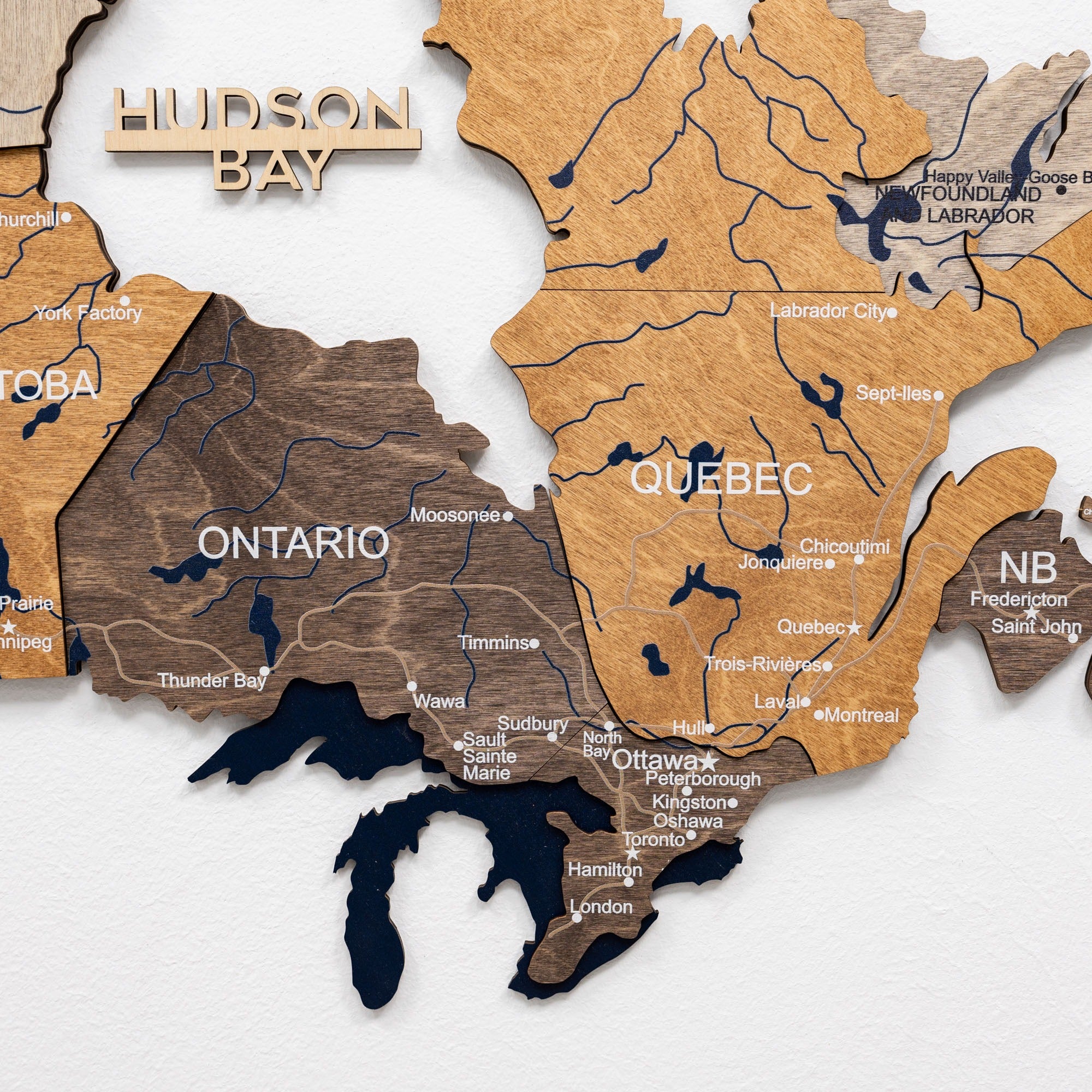 Wooden map of Canada with provinces labeled on a white background