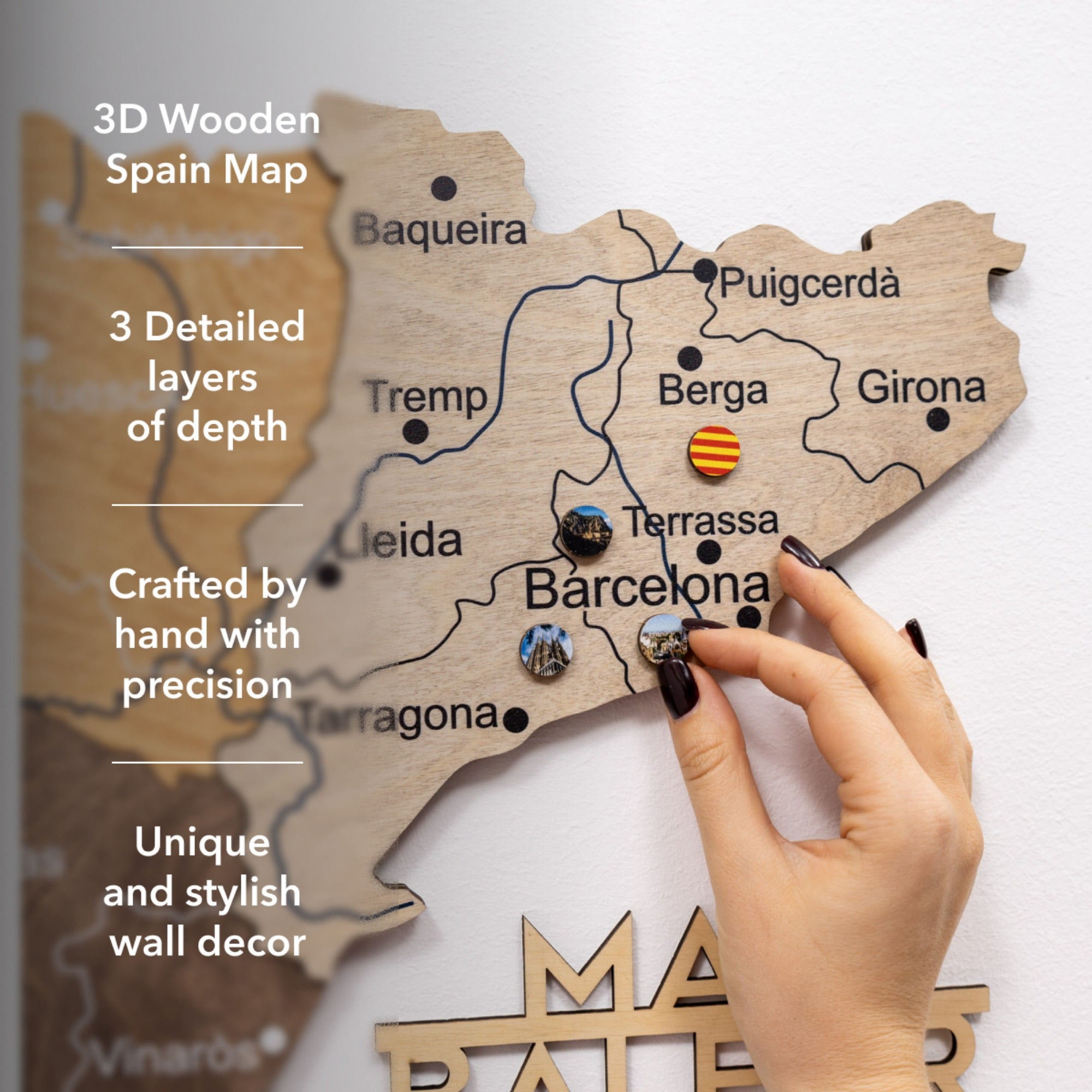 Wooden map of Spain with detailed text and a hand placing decorative pins.