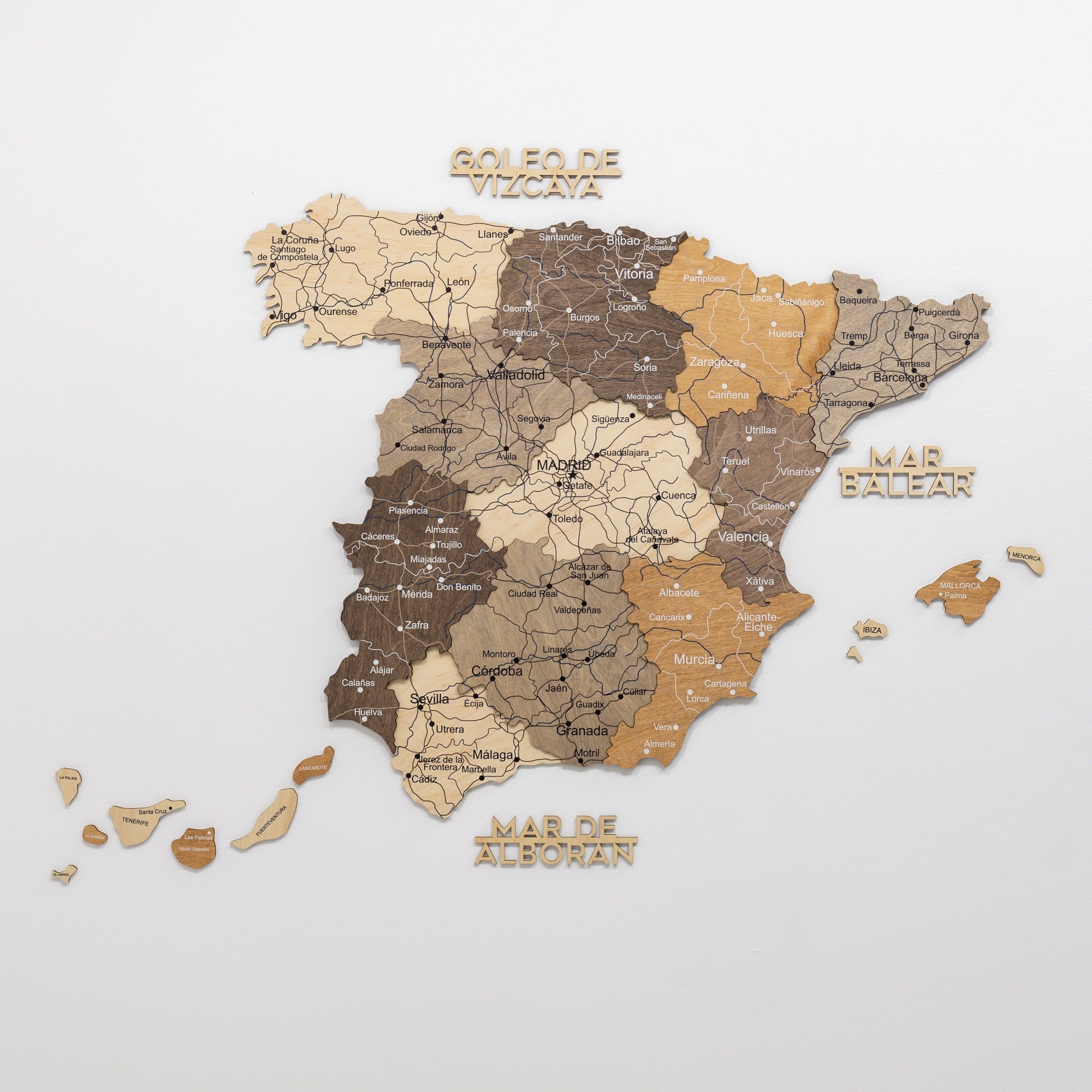 Wooden map of Spain with different regions labeled on a white background