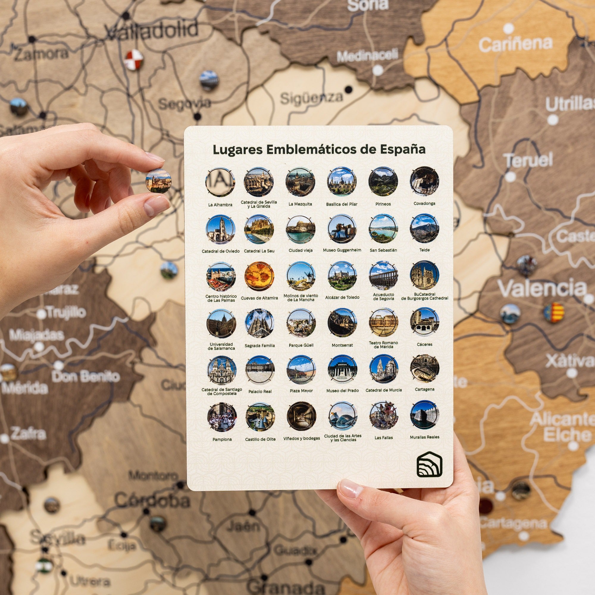 Sheet of stickers with emblematic places of Spain held over a map