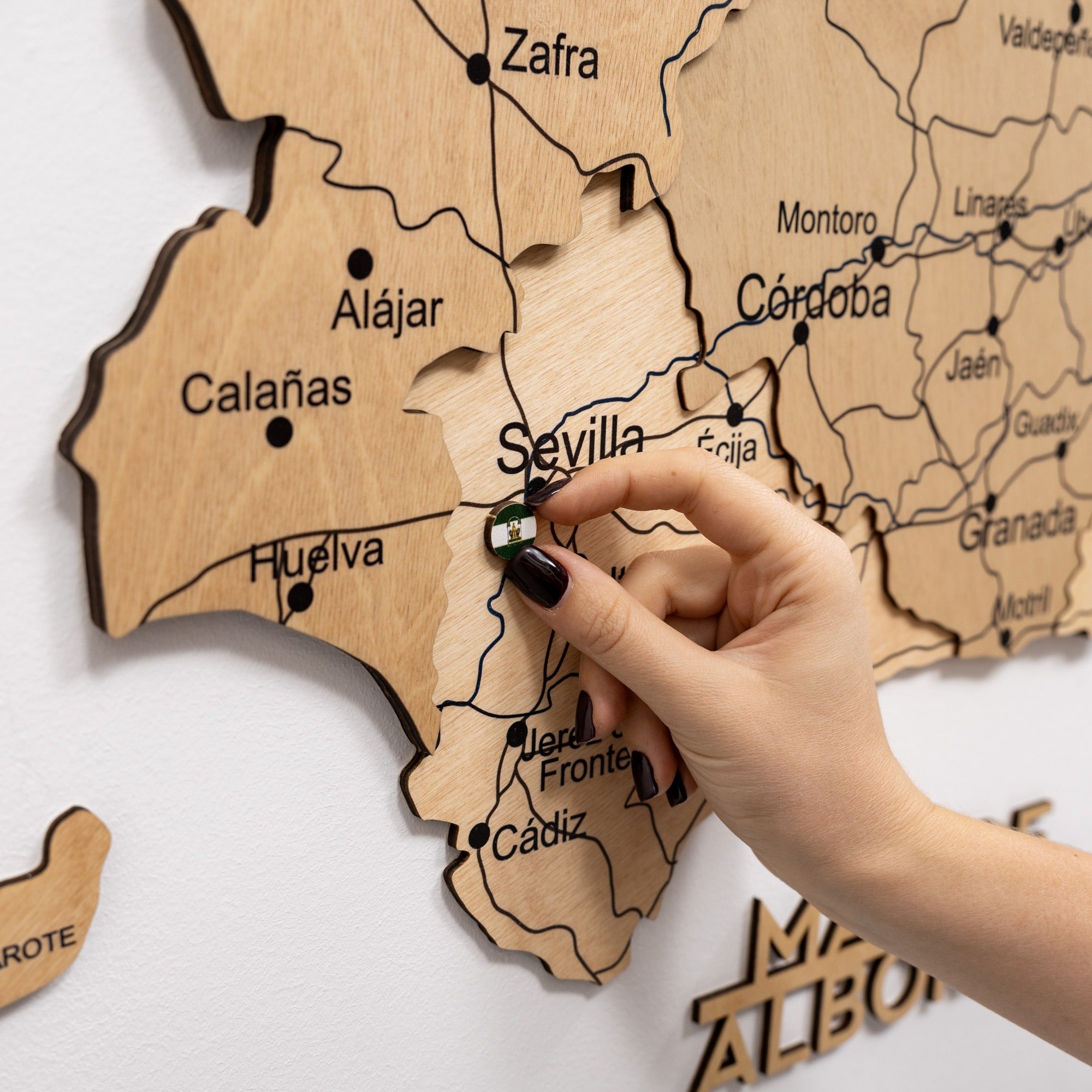 Wooden map of Spain with a hand pointing to Seville