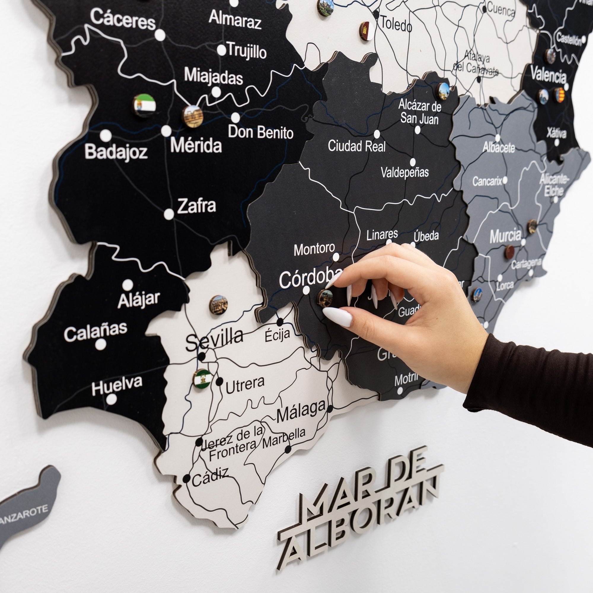 Map of Spain with regions labeled, showing a hand placing a pin on the map.