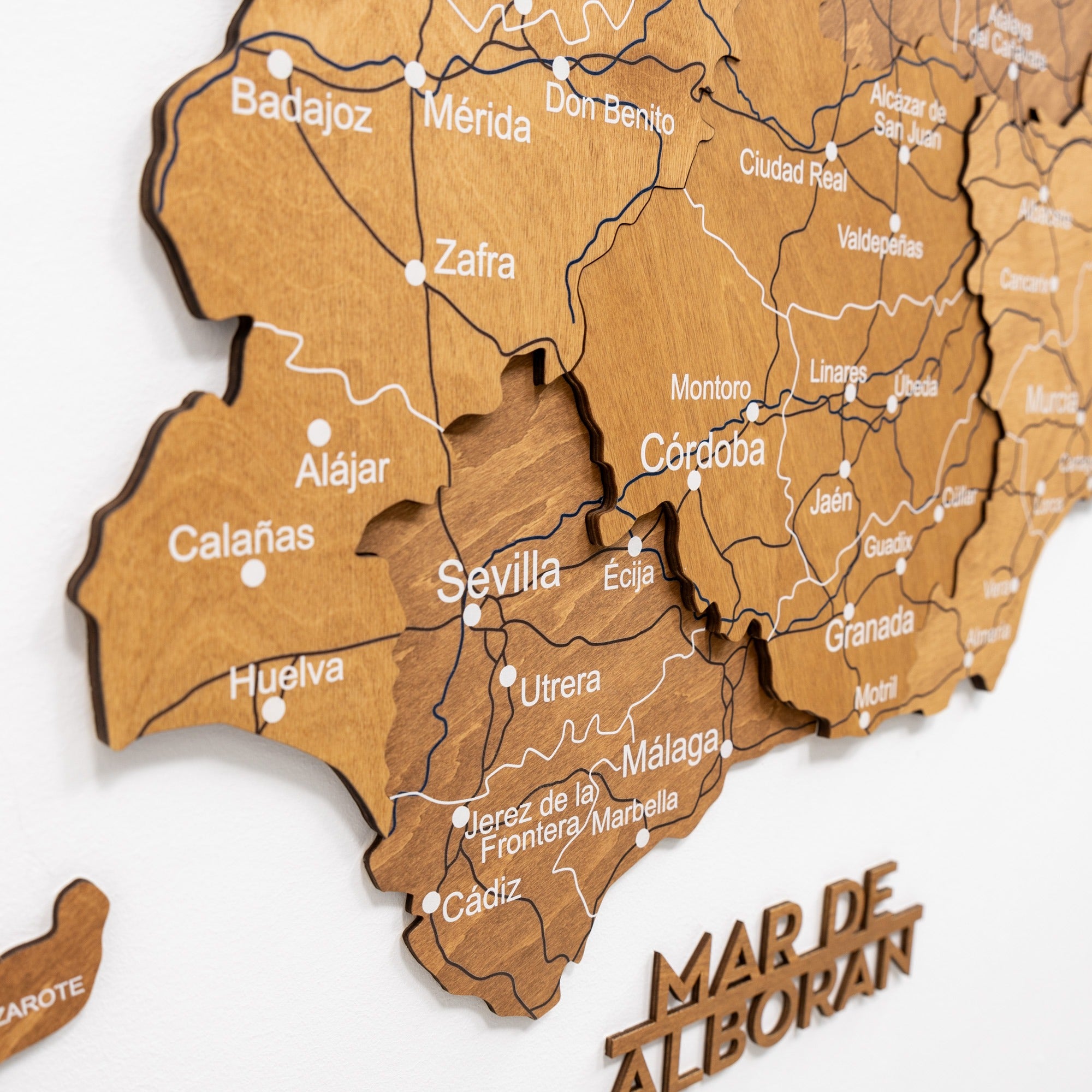 Wooden map of Andalusia with cities labeled on a white background