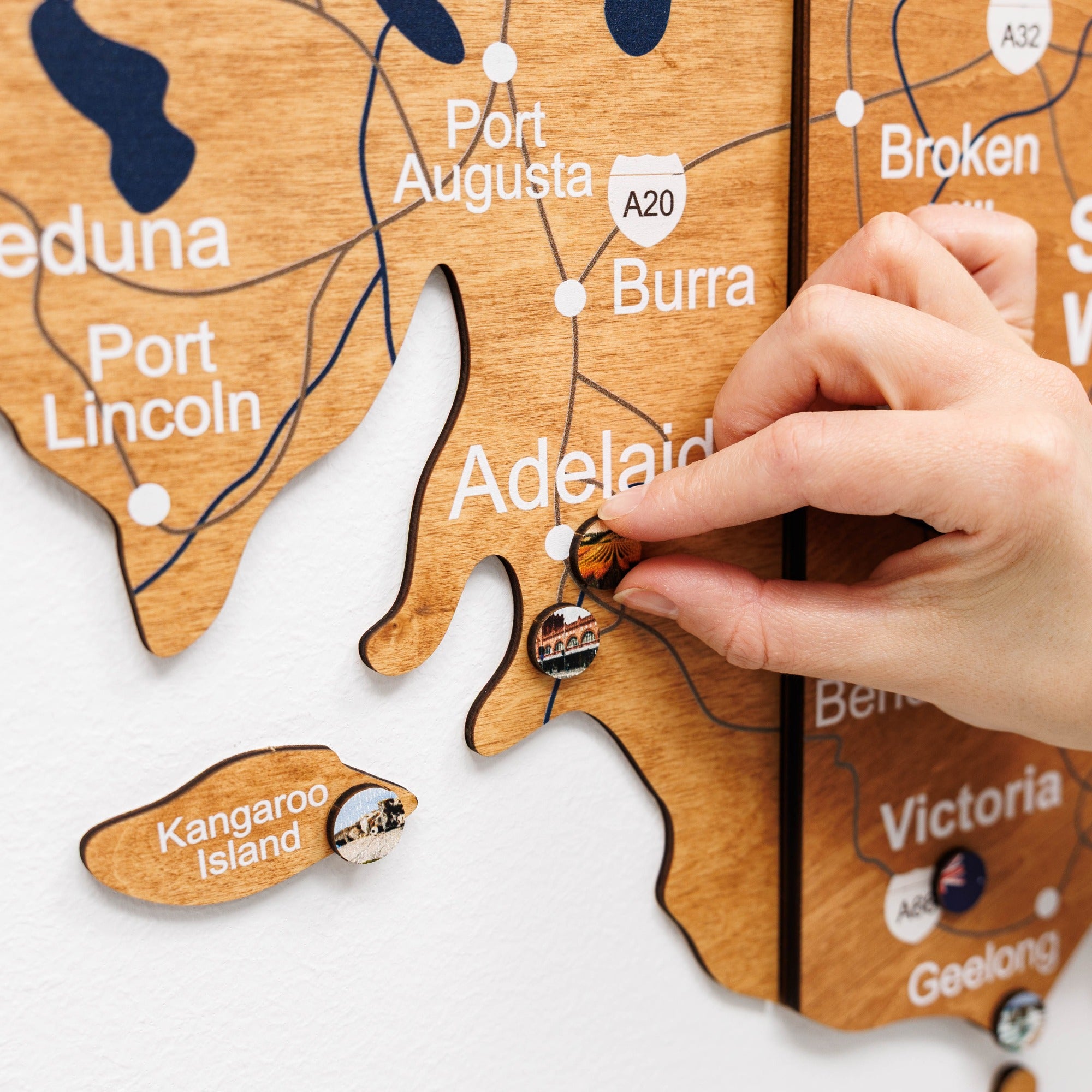 Hand placing a small wooden ornament on a wooden map of Australia.