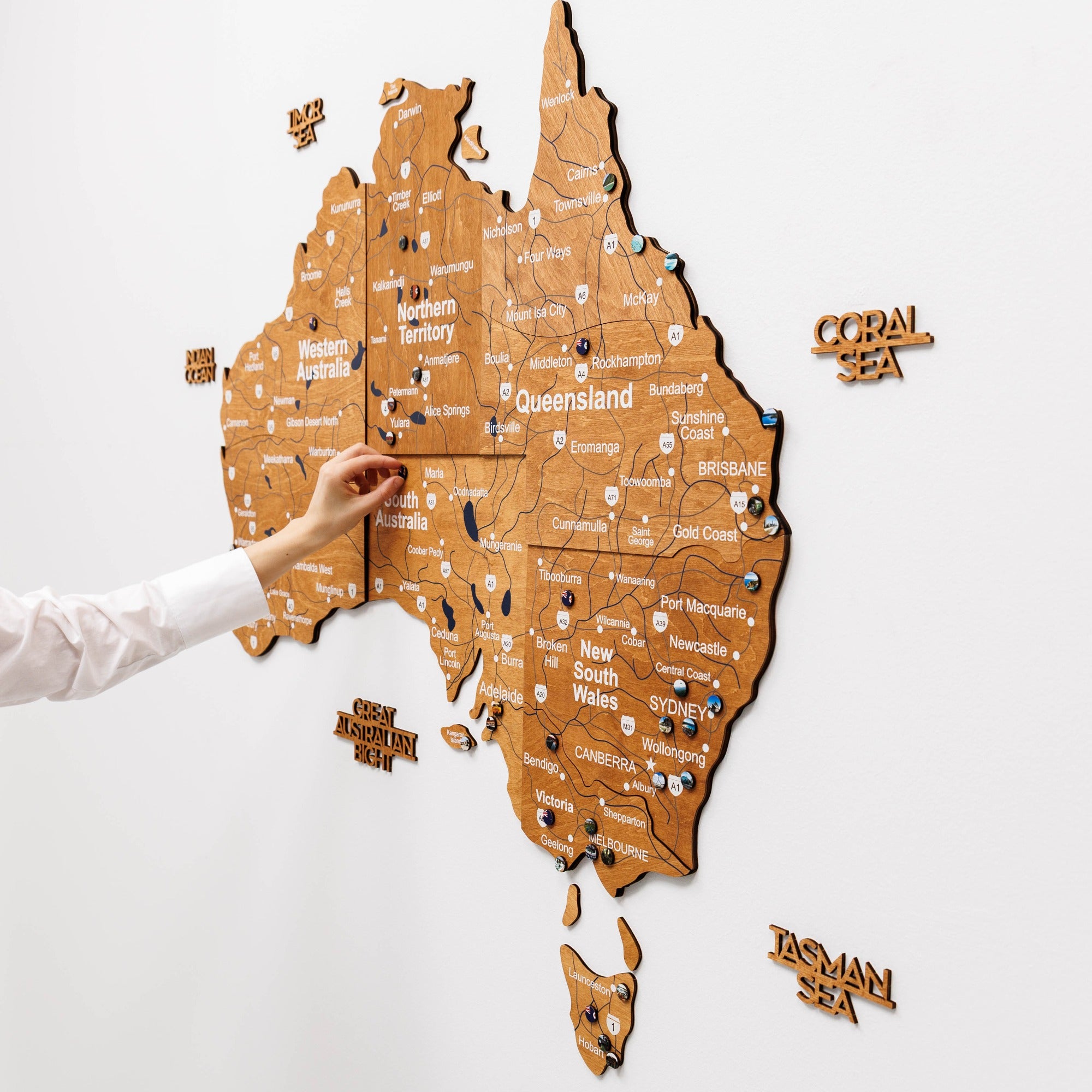 Wooden map of Australia with pins on a white wall