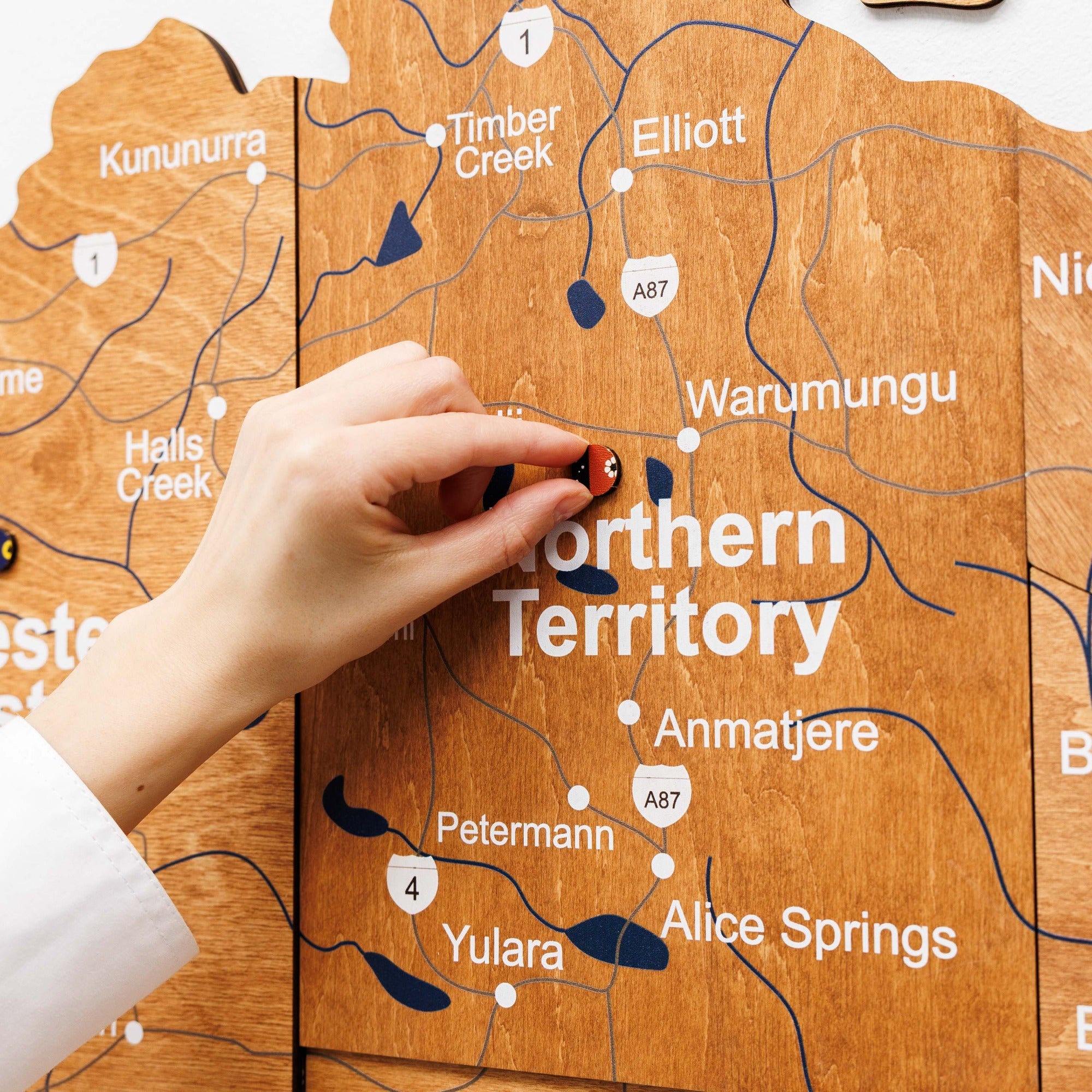 Hand placing a small object on a wooden map of the Northern Territory.