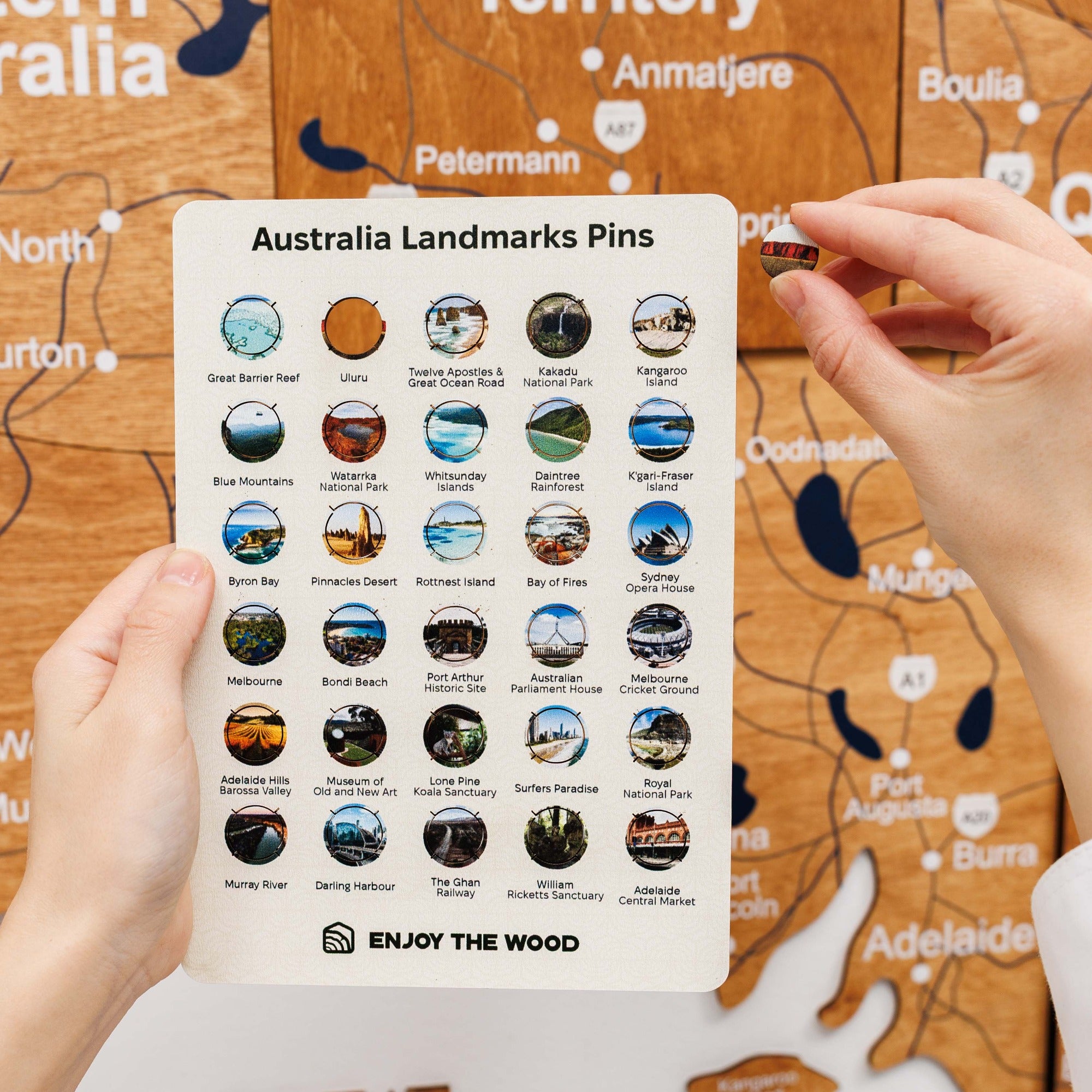 Sheet of Australia Landmarks Pins held by a hand with a map in the background