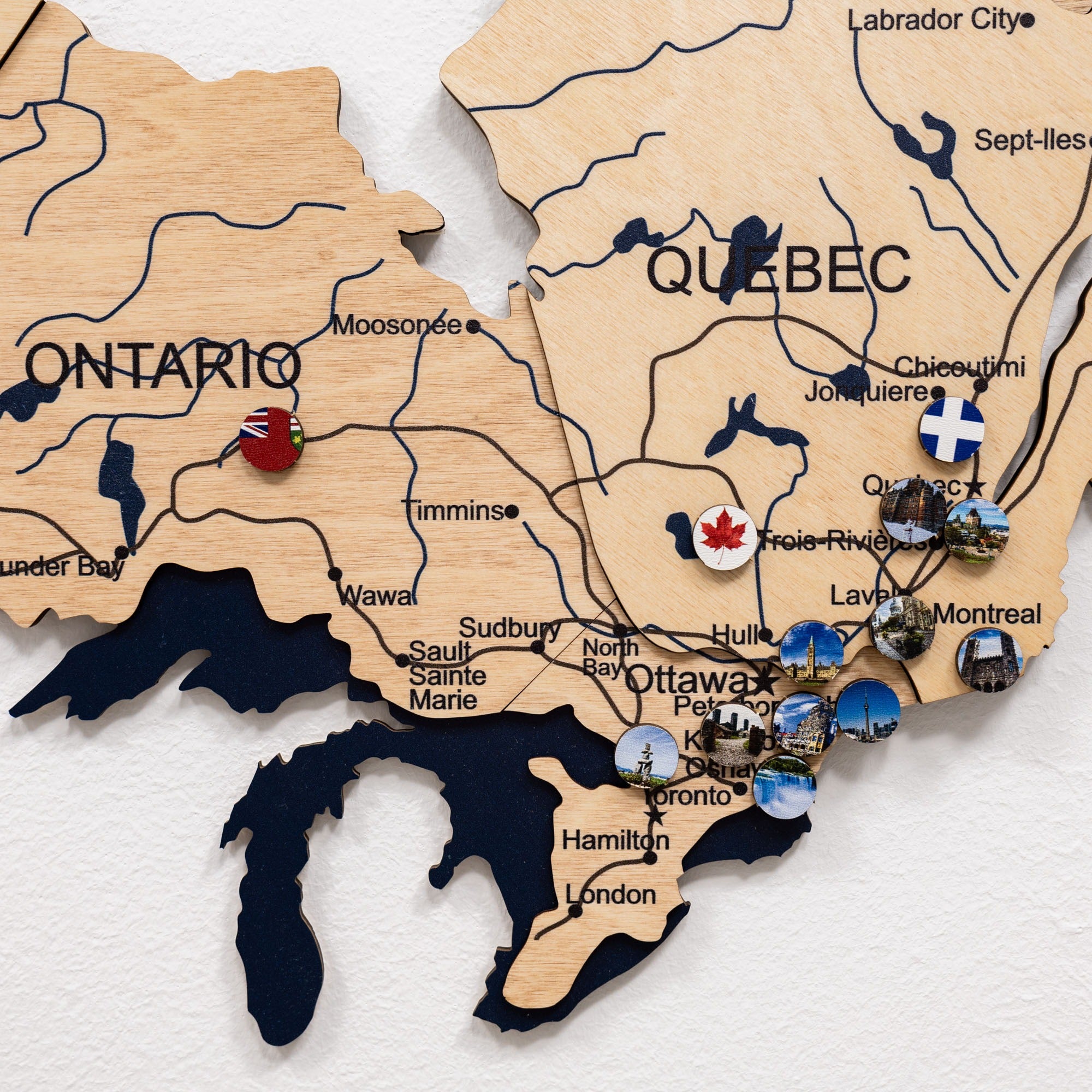 Wooden map of Canada with various locations marked by pins.