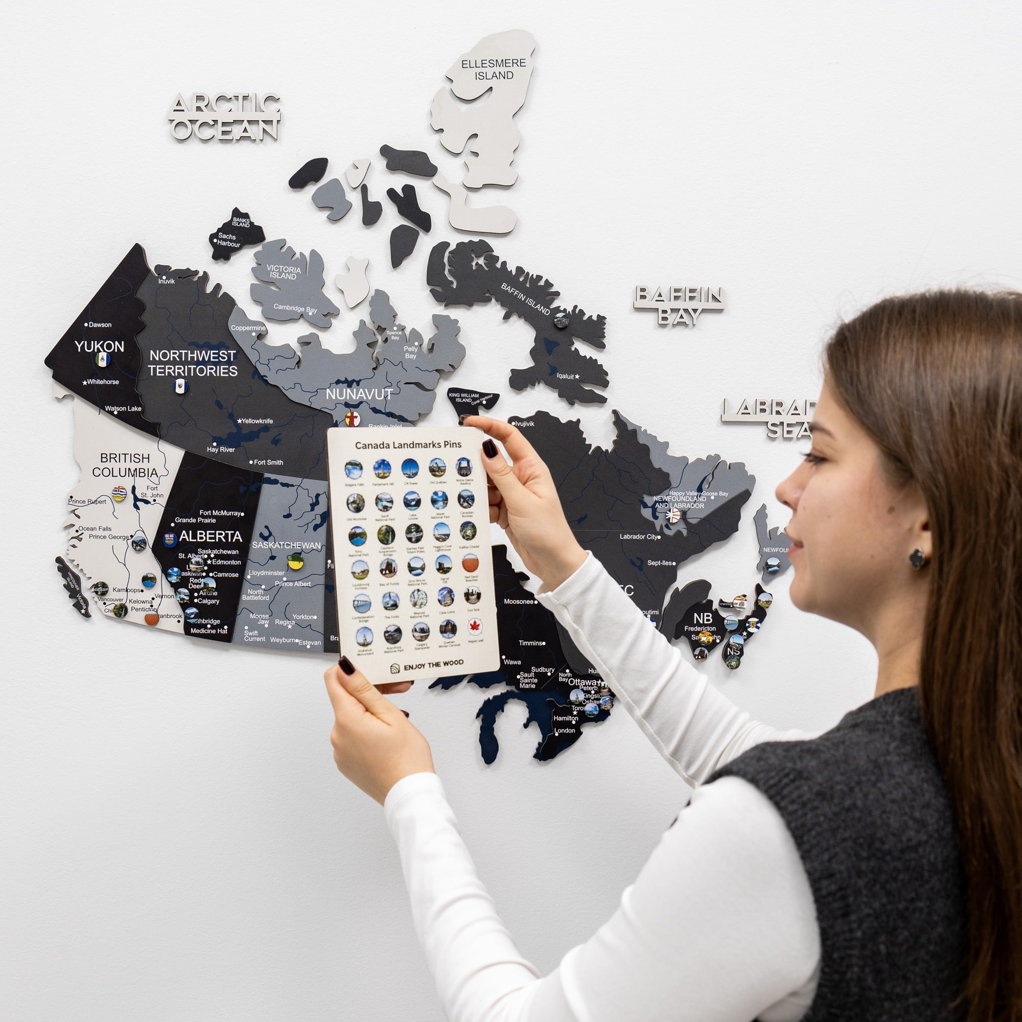 Woman looking at a travel map with magnets on a white wall