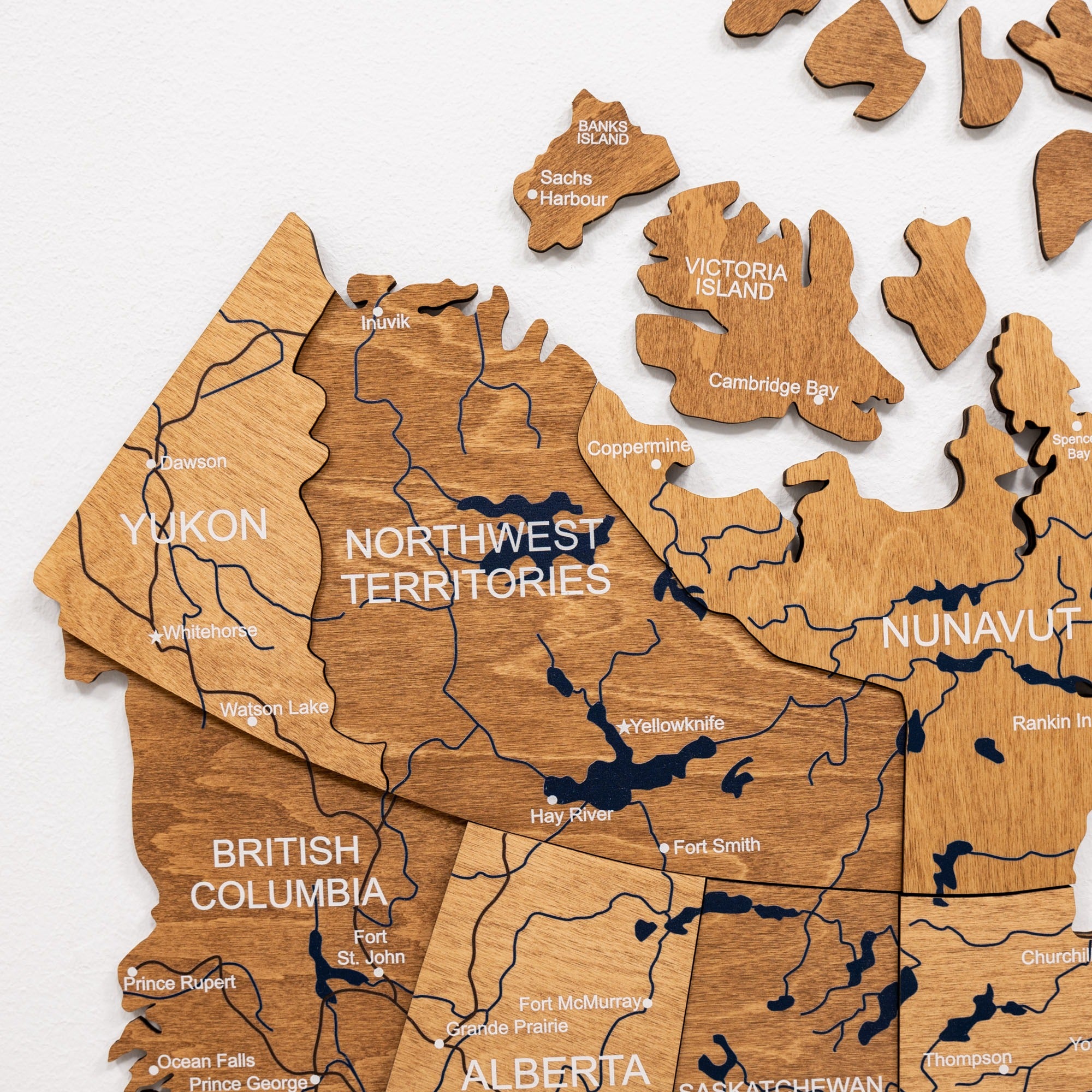 Wooden map of Canada with provinces and territories labeled on a white background