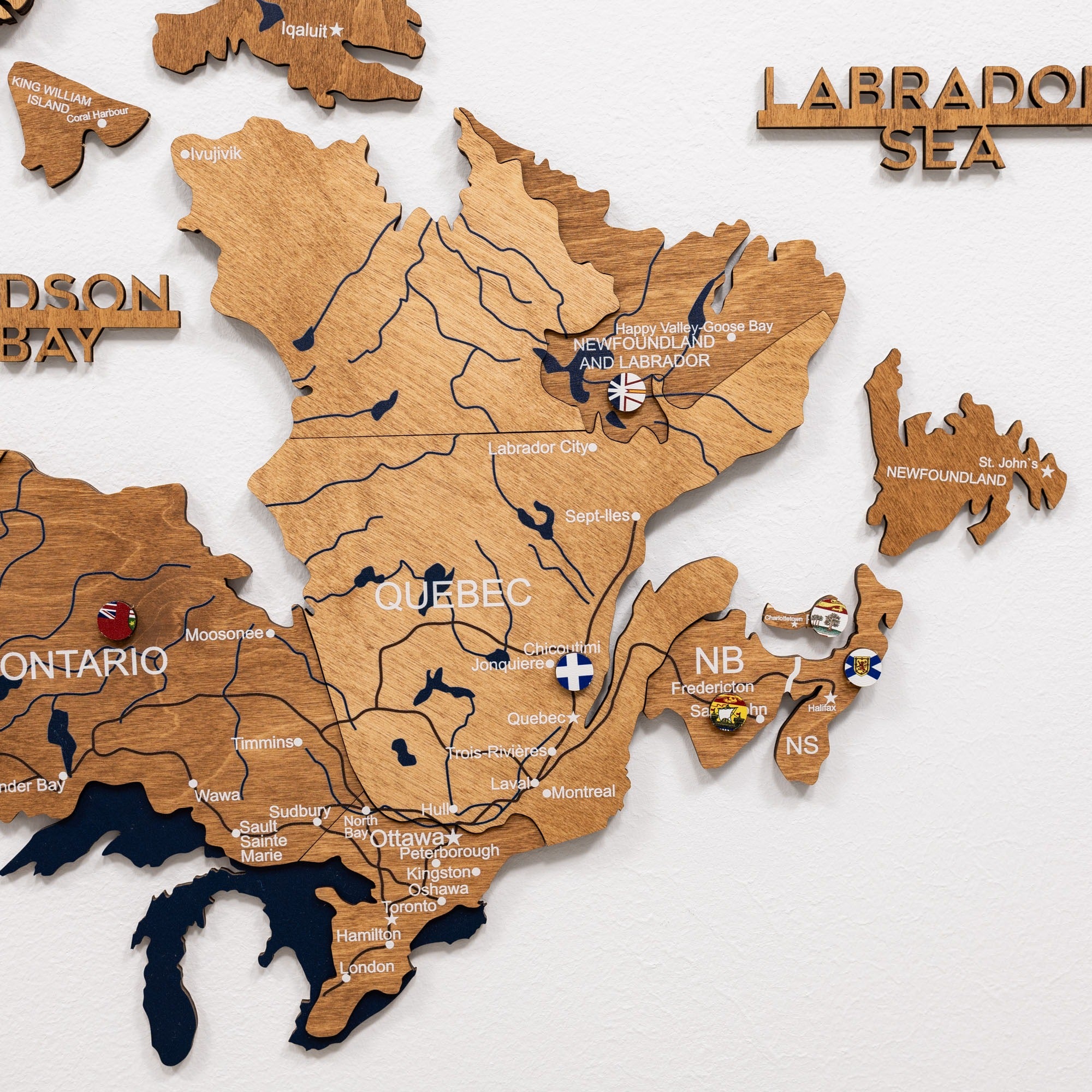 Wooden map of Canada with provinces labeled on a white background