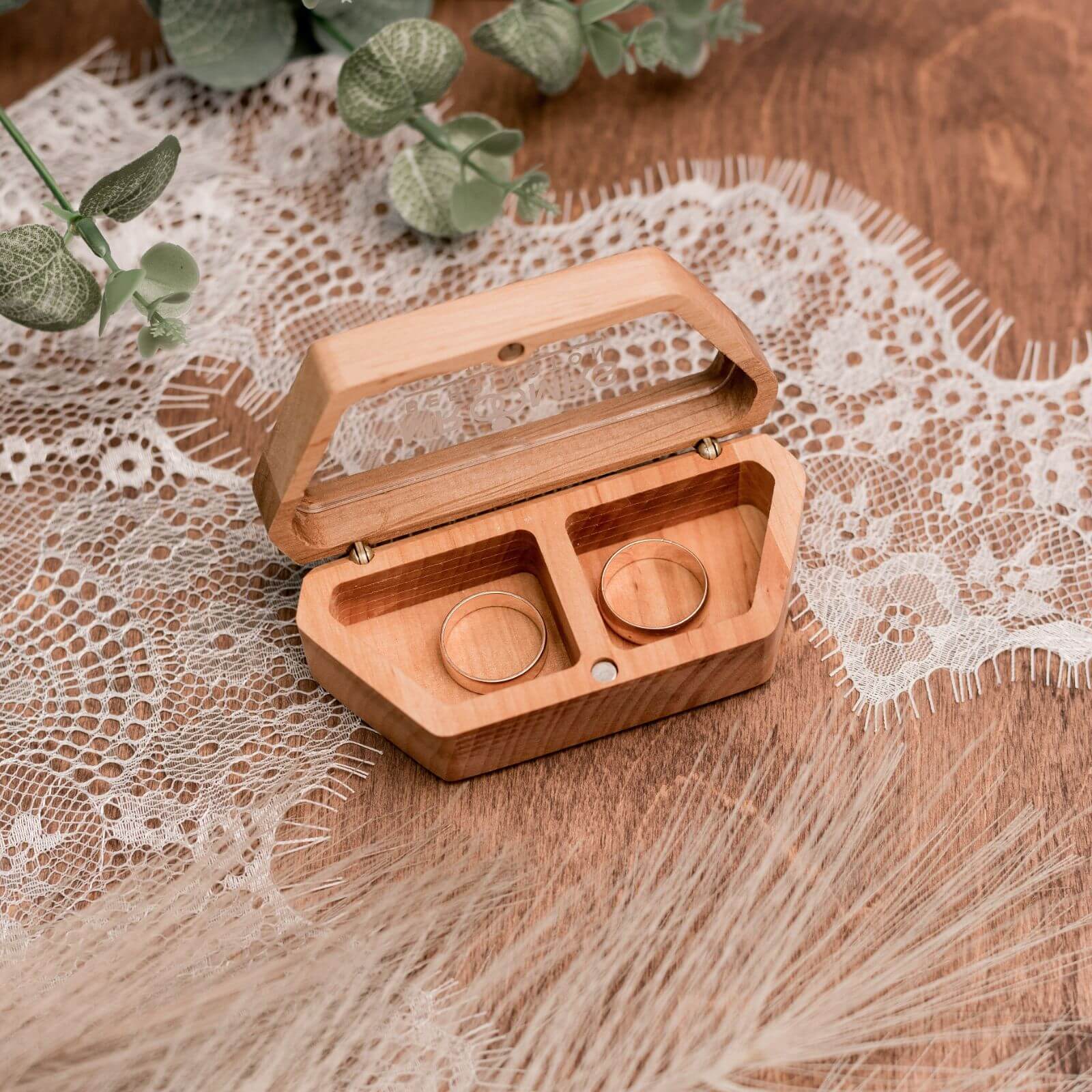 Handmade wooden wedding ring box with two gold rings inside.