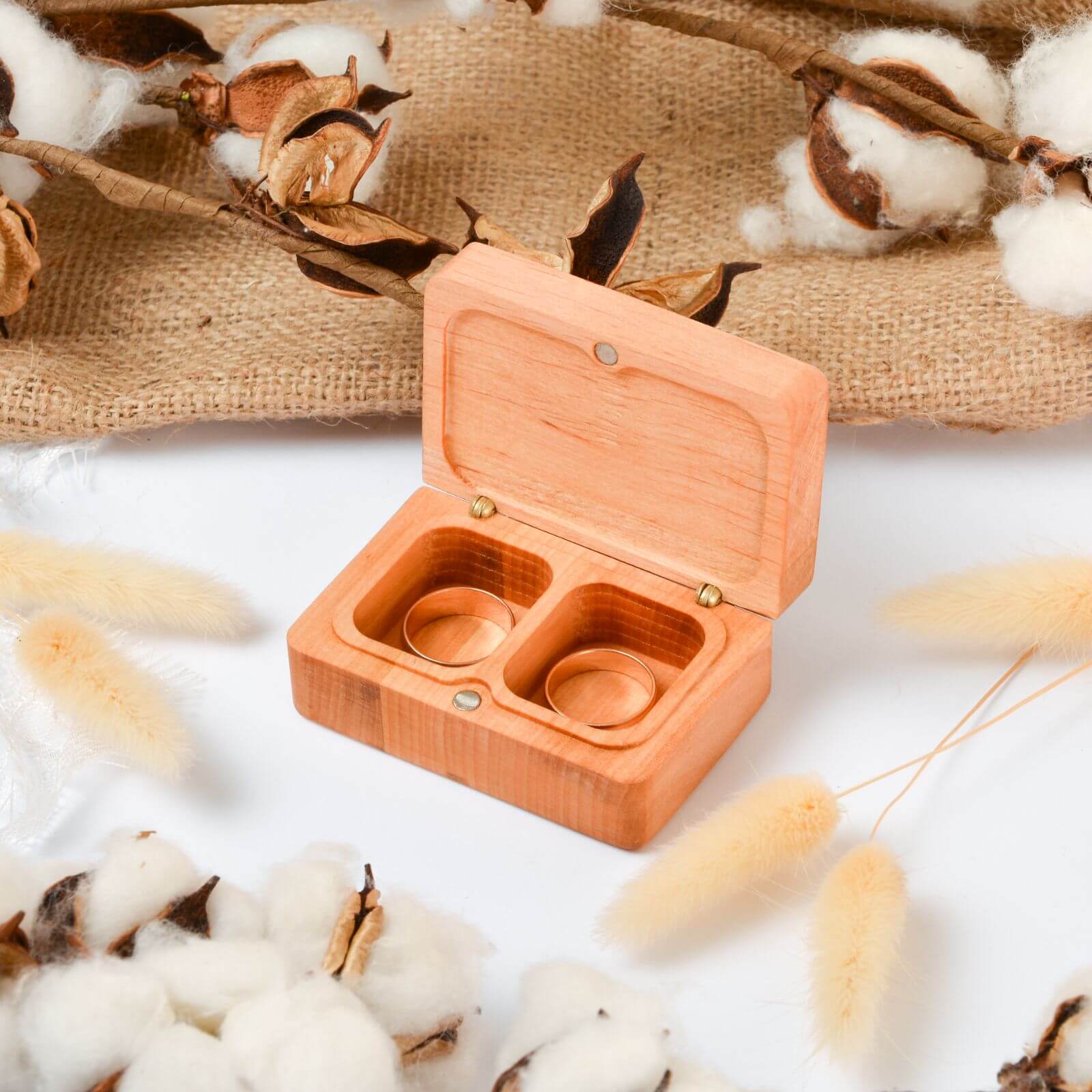 Open wooden double ring box with rustic cotton decor.