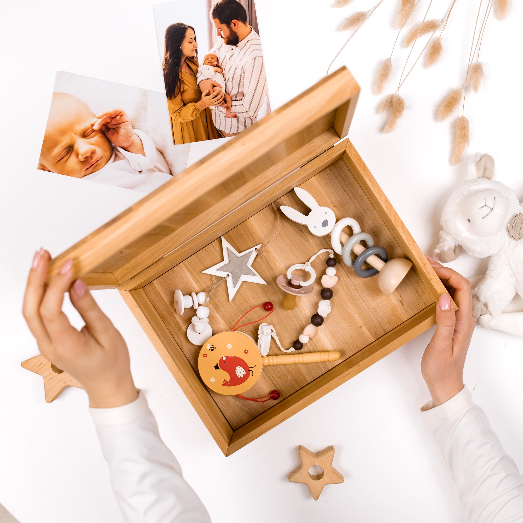 Wooden baby toy box with toys and photos of a baby on a white surface