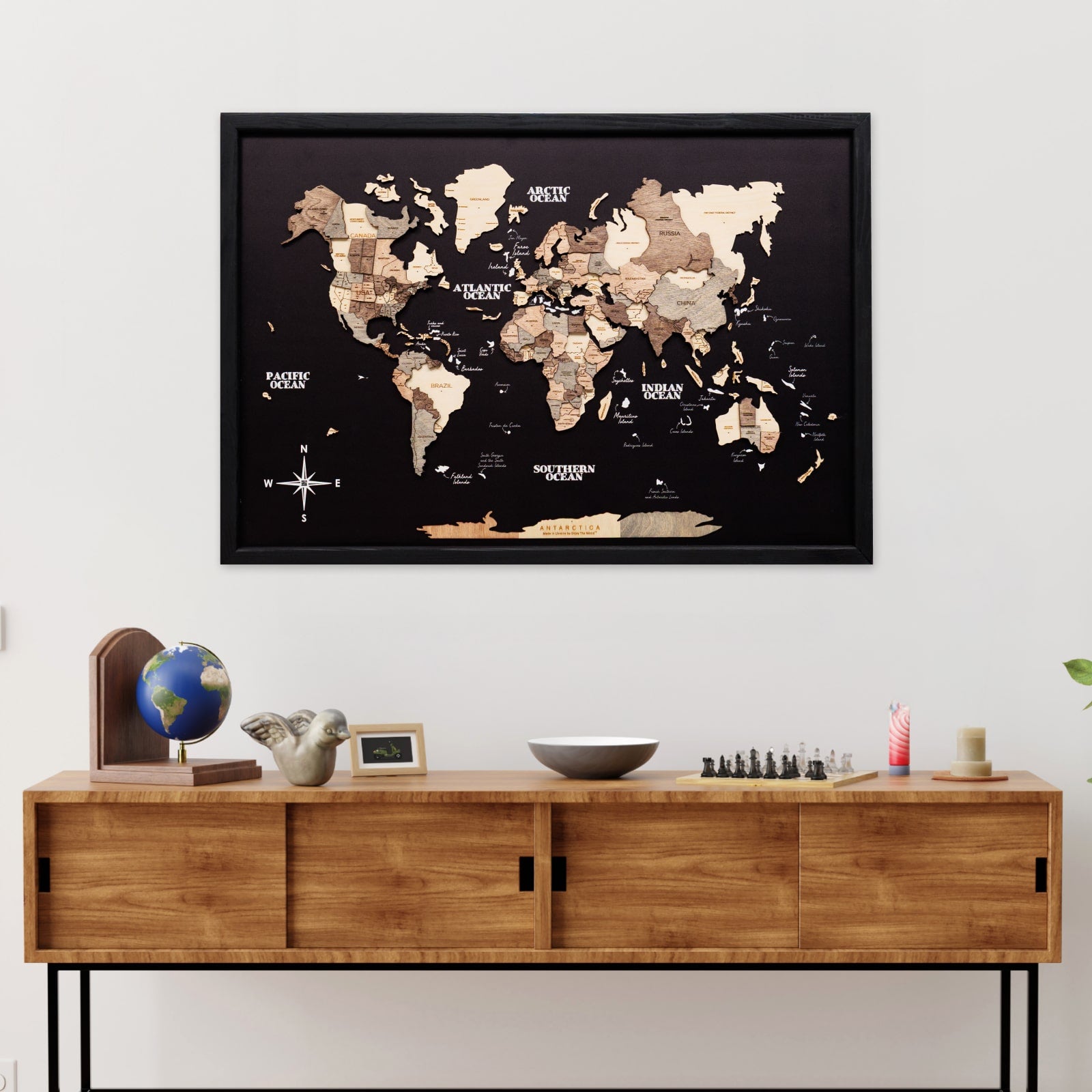 World map poster on a wall above a wooden cabinet with decorative items.