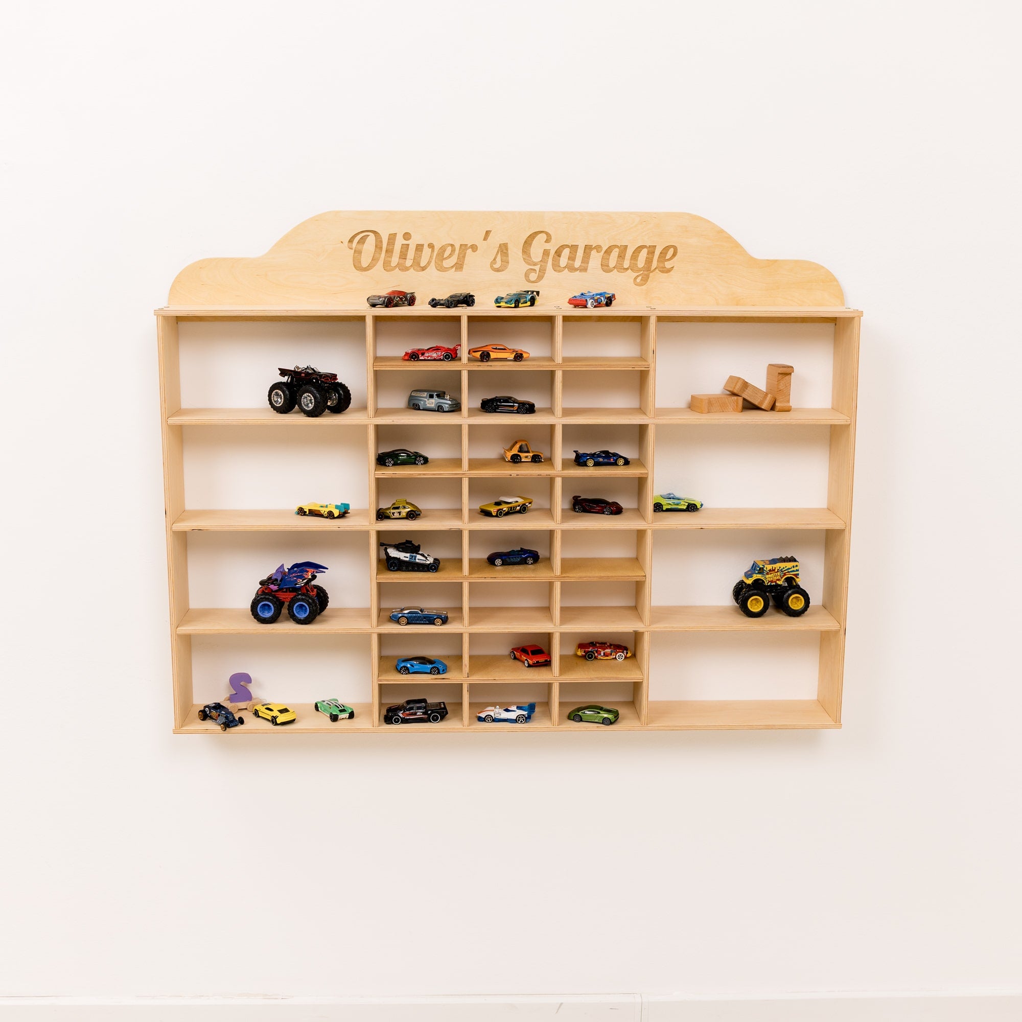 Wooden toy car display shelf with 'Oliver's Garage' on a white wall