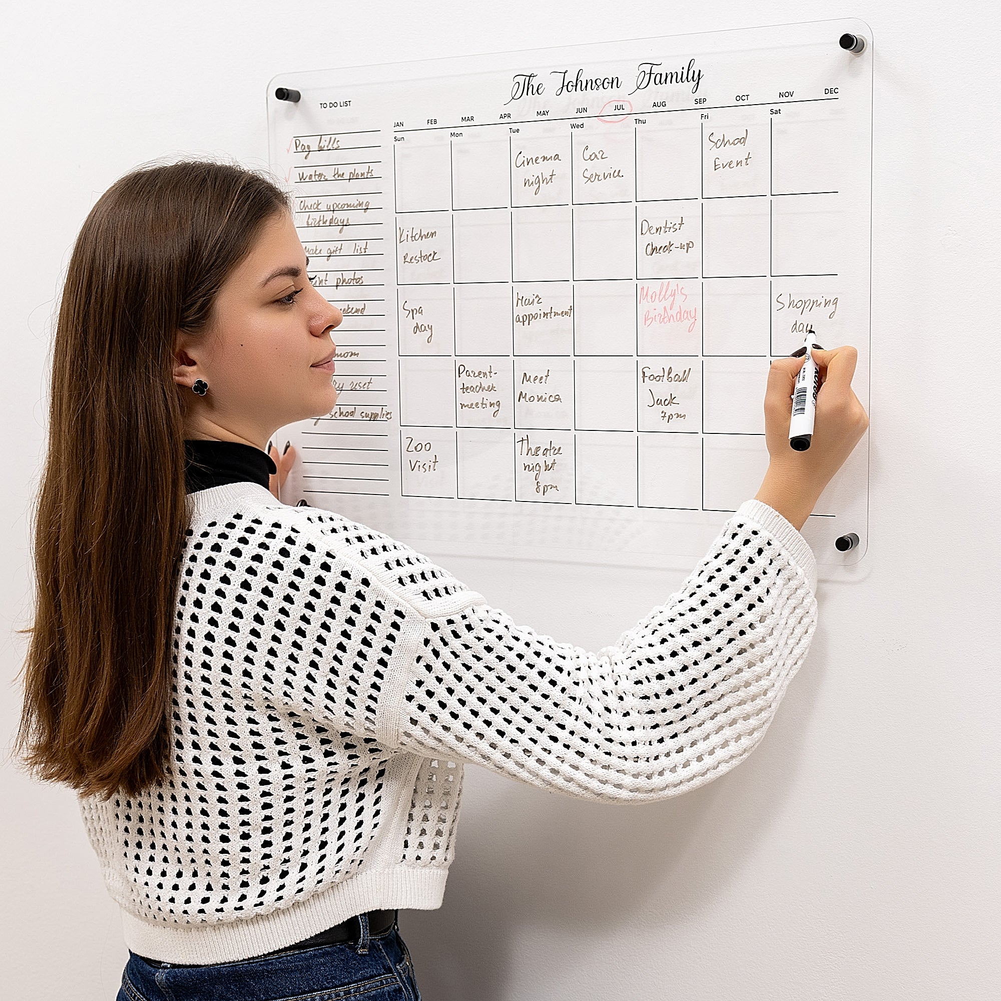 Woman writing on a family calendar on a white wall