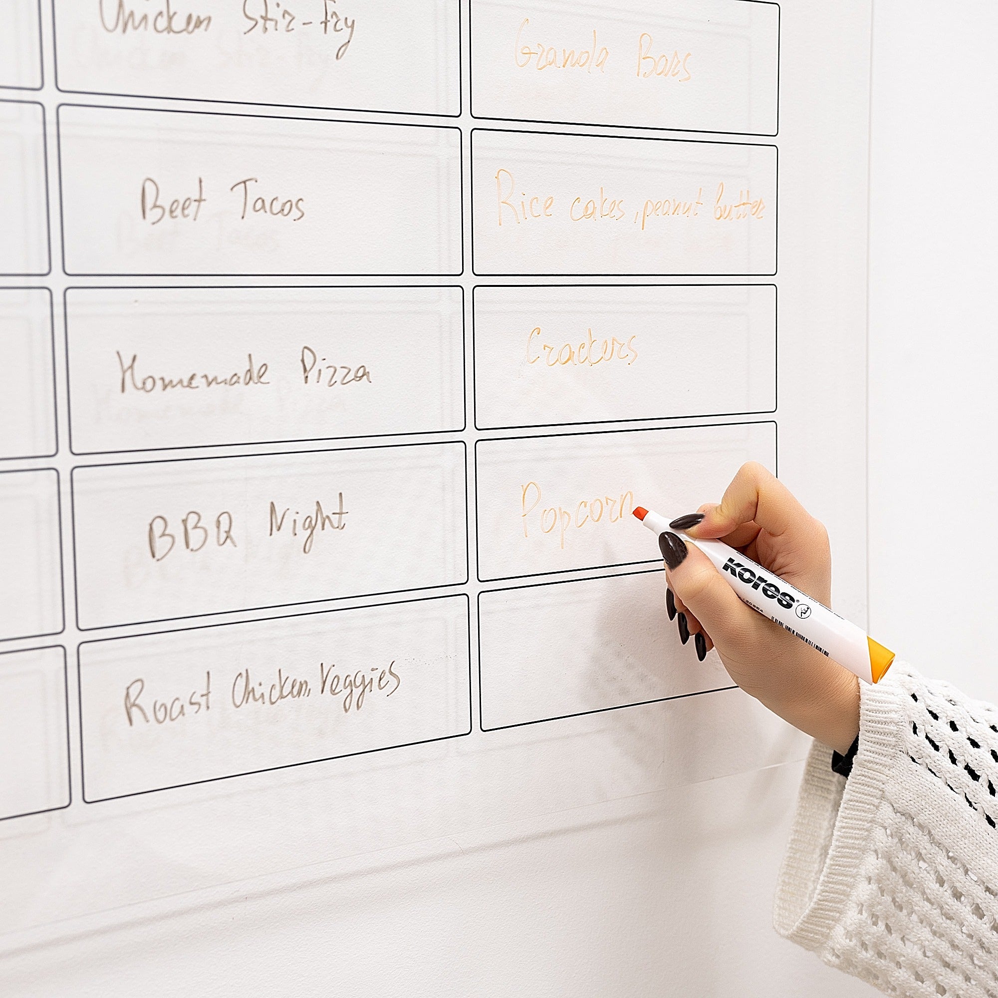 Hand writing on a whiteboard with meal planning labels