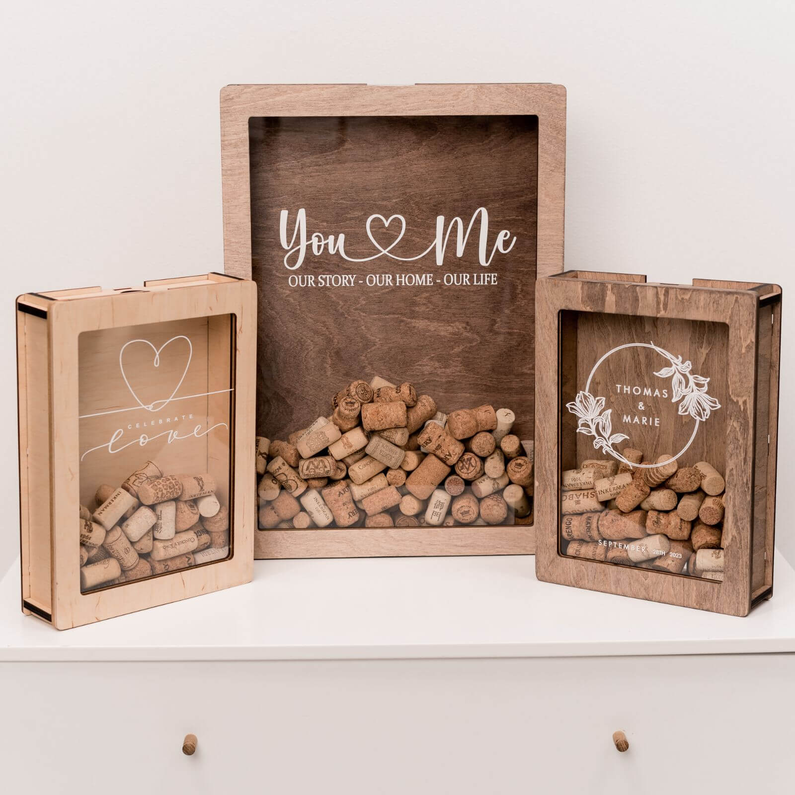 A set of wooden card boxes with glass windows, designed for wedding cards. They vary in size and have a heart design with the text 'You Me Our Story Our Home Our Life' printed on one of them.