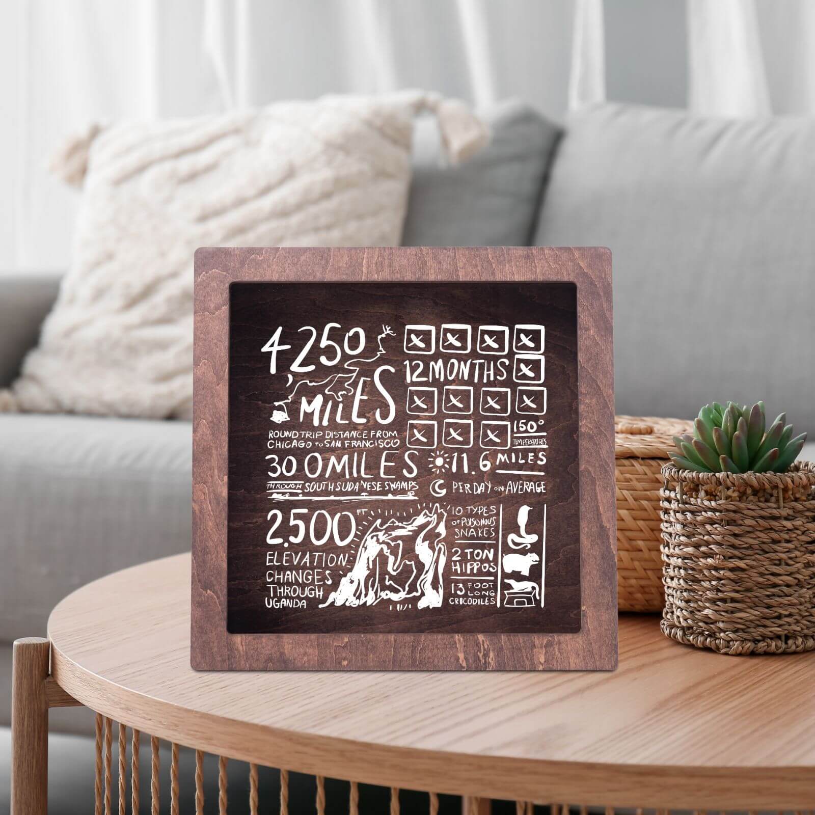 A wooden wine cork box with a glass front displaying text and a wine tap illustration, placed on a table with wine glasses and bottles in the background.