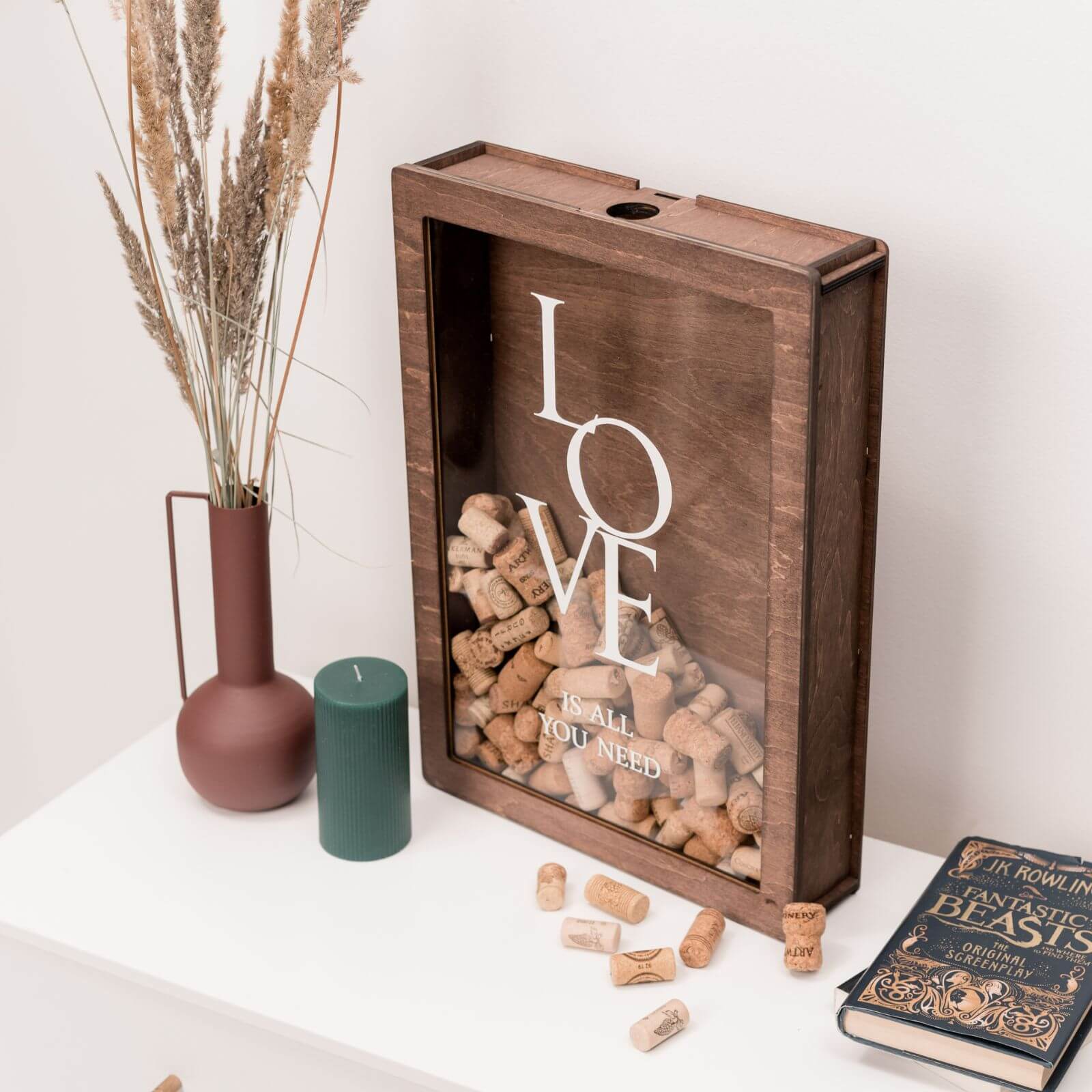 Large wooden shadow box filled with wine corks, engraved “LOVE is all you need.”