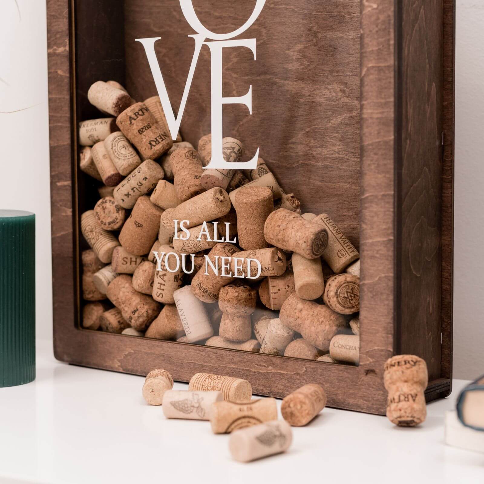 Wooden shadow box for wine corks with “LOVE is all you need” engraving, filled with corks.