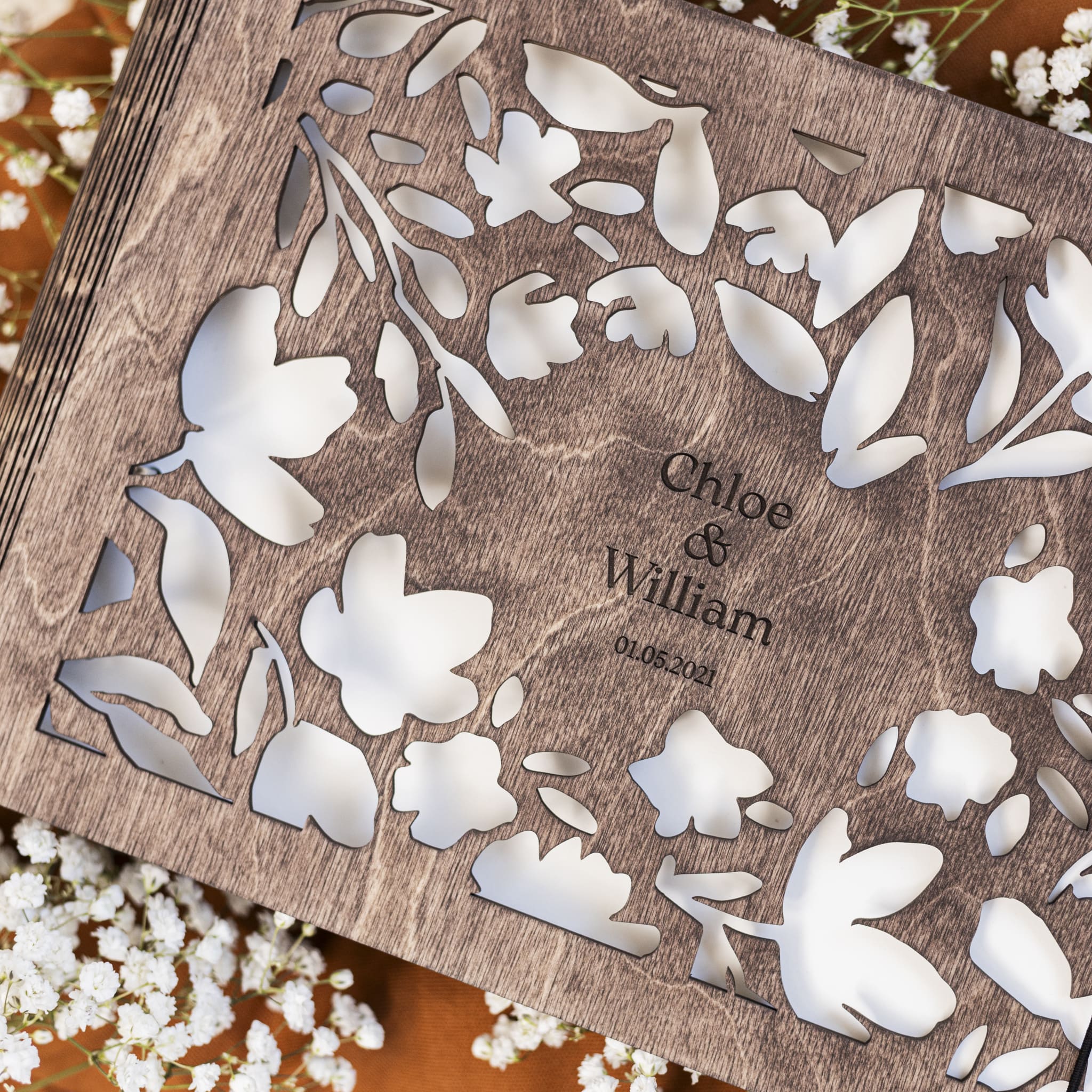 Wooden box with floral cutout design and engraved names 'Chloe & William' on a wooden surface.