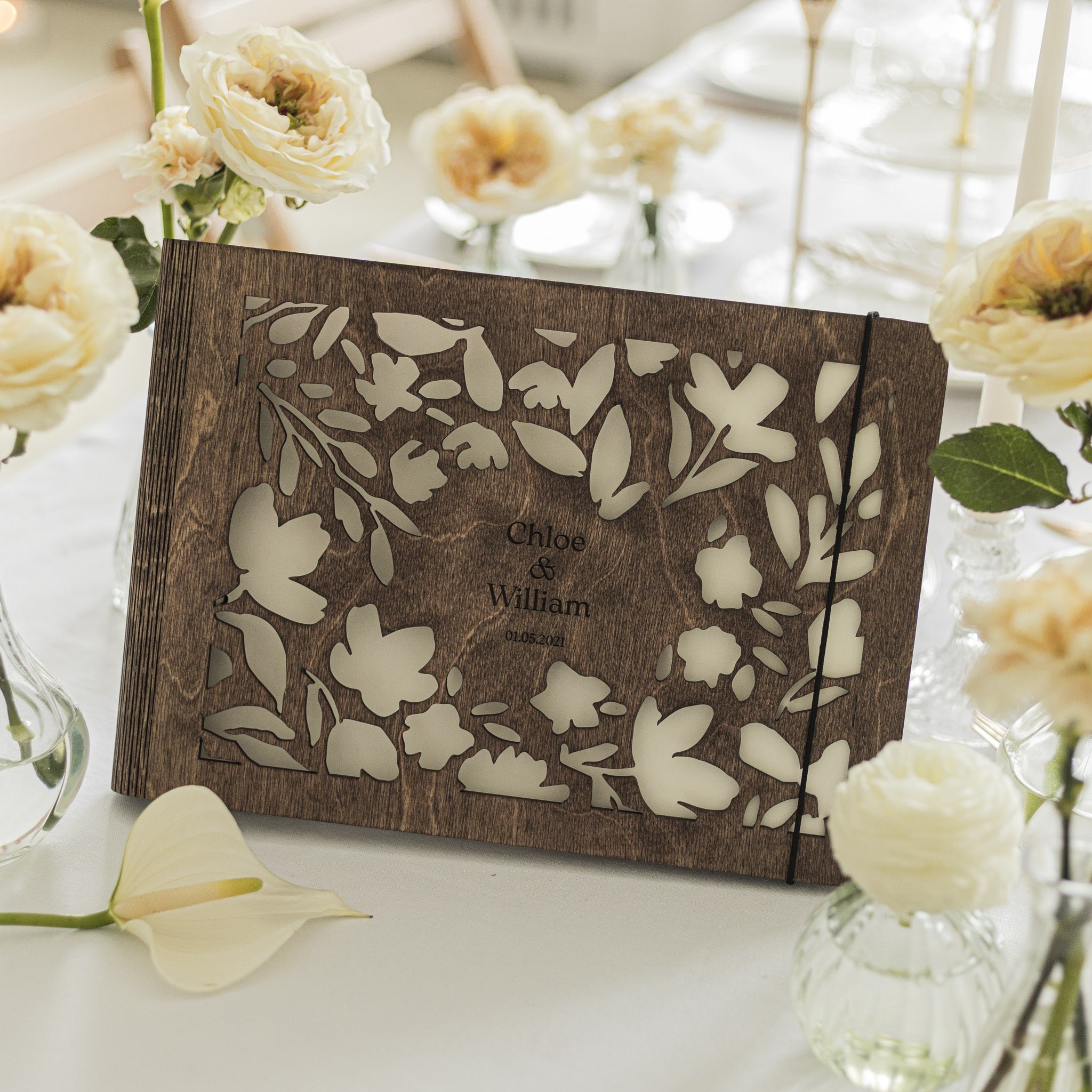 Wooden photo album with floral design on a table with white flowers