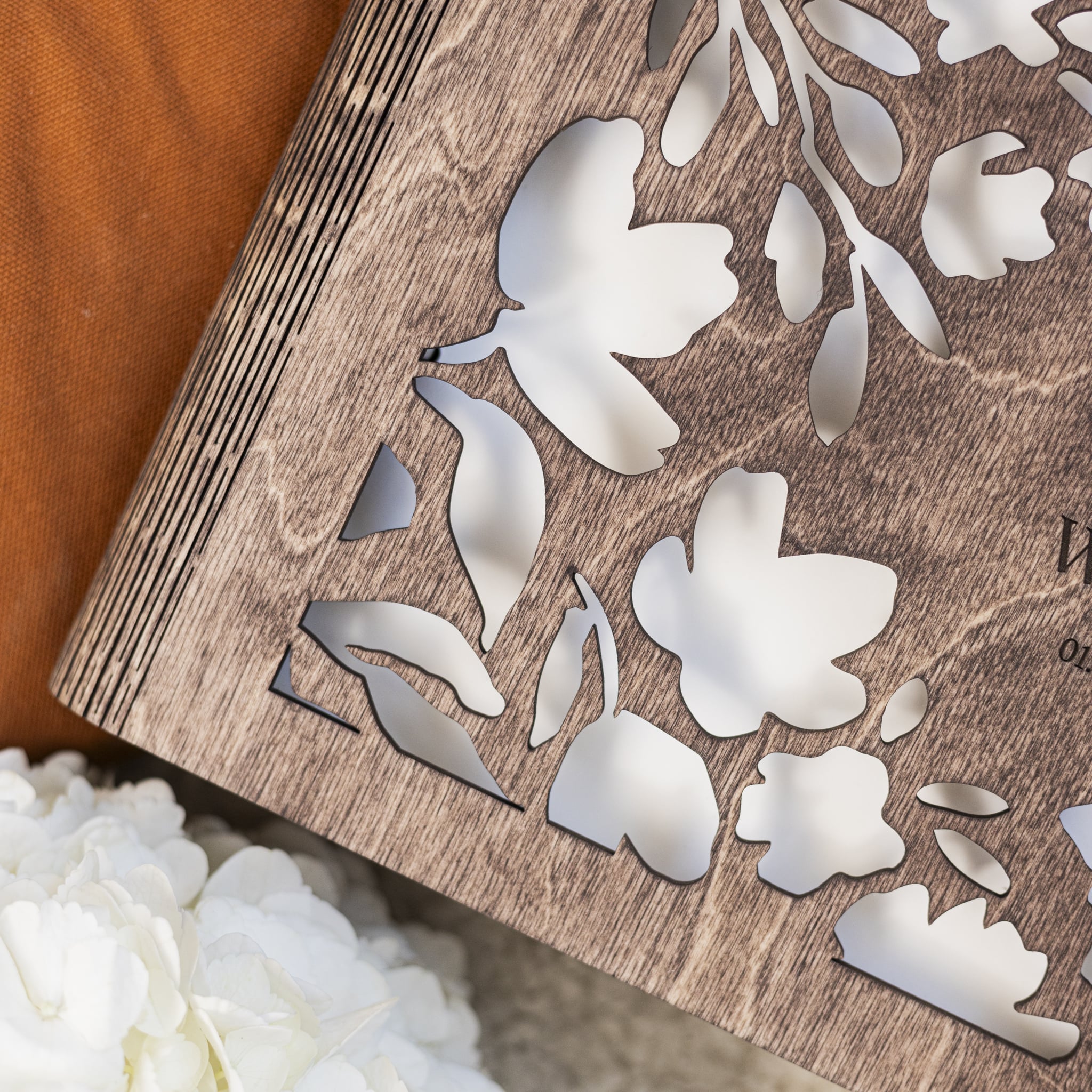 Wooden plaque with cut-out white floral designs on a soft fabric background