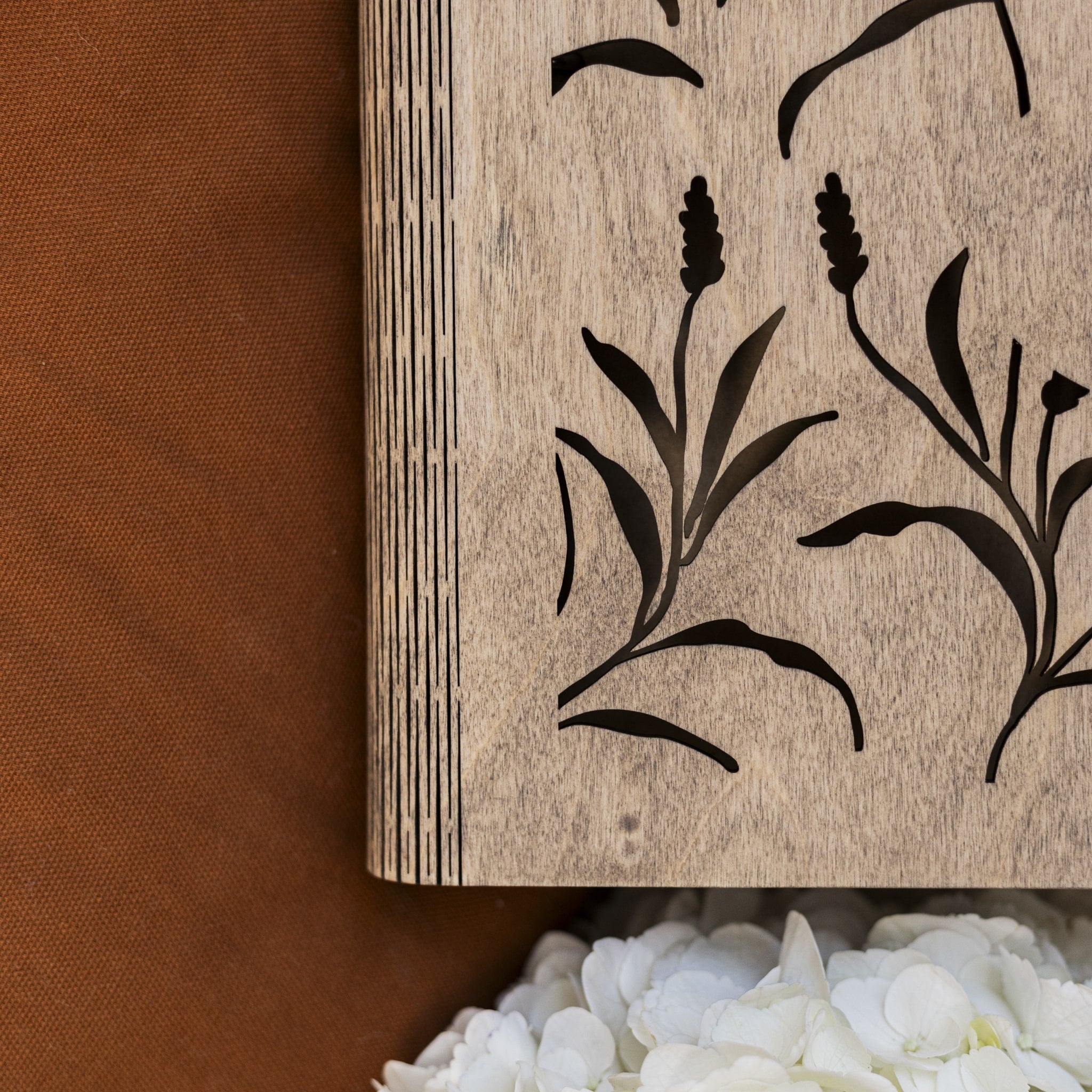 Wooden block with black floral design on a brown fabric background