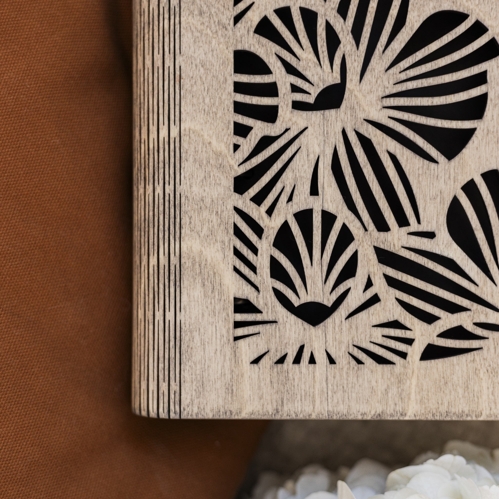Wooden coaster with black leaf pattern on a brown surface