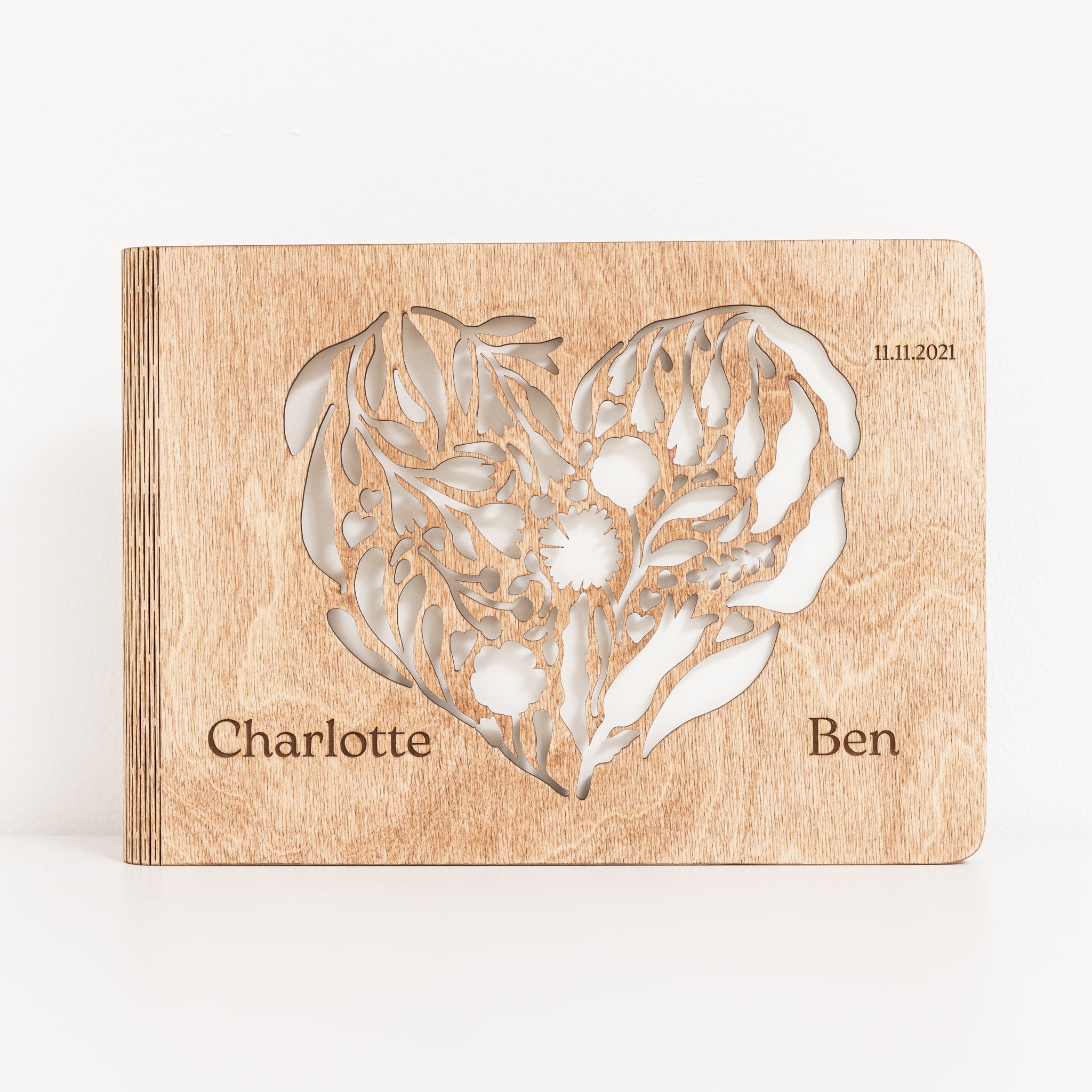 Wooden photo album with floral design and engraved names on a white background