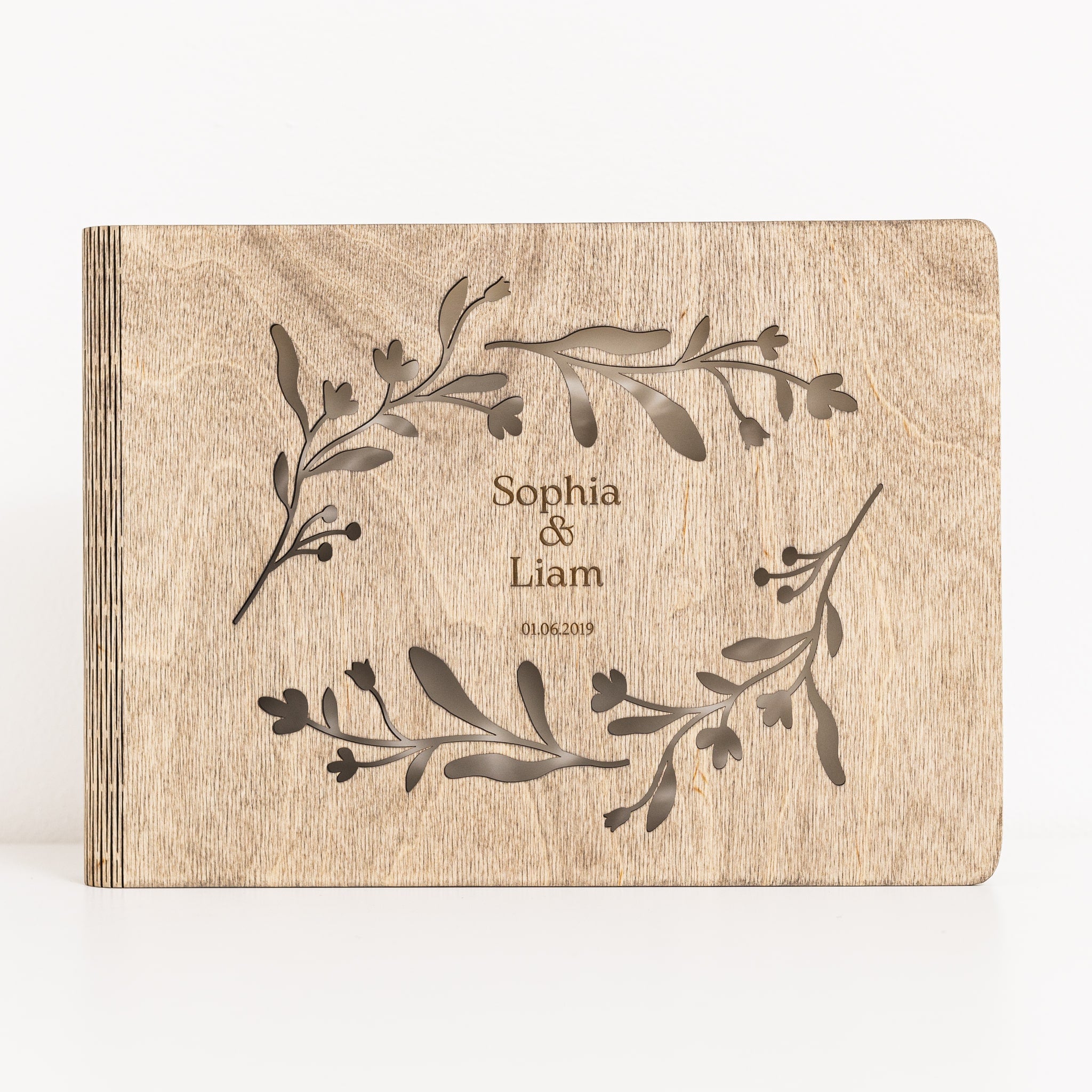 Wooden album with engraved floral design and names 'Sophia & Liam' on a white background