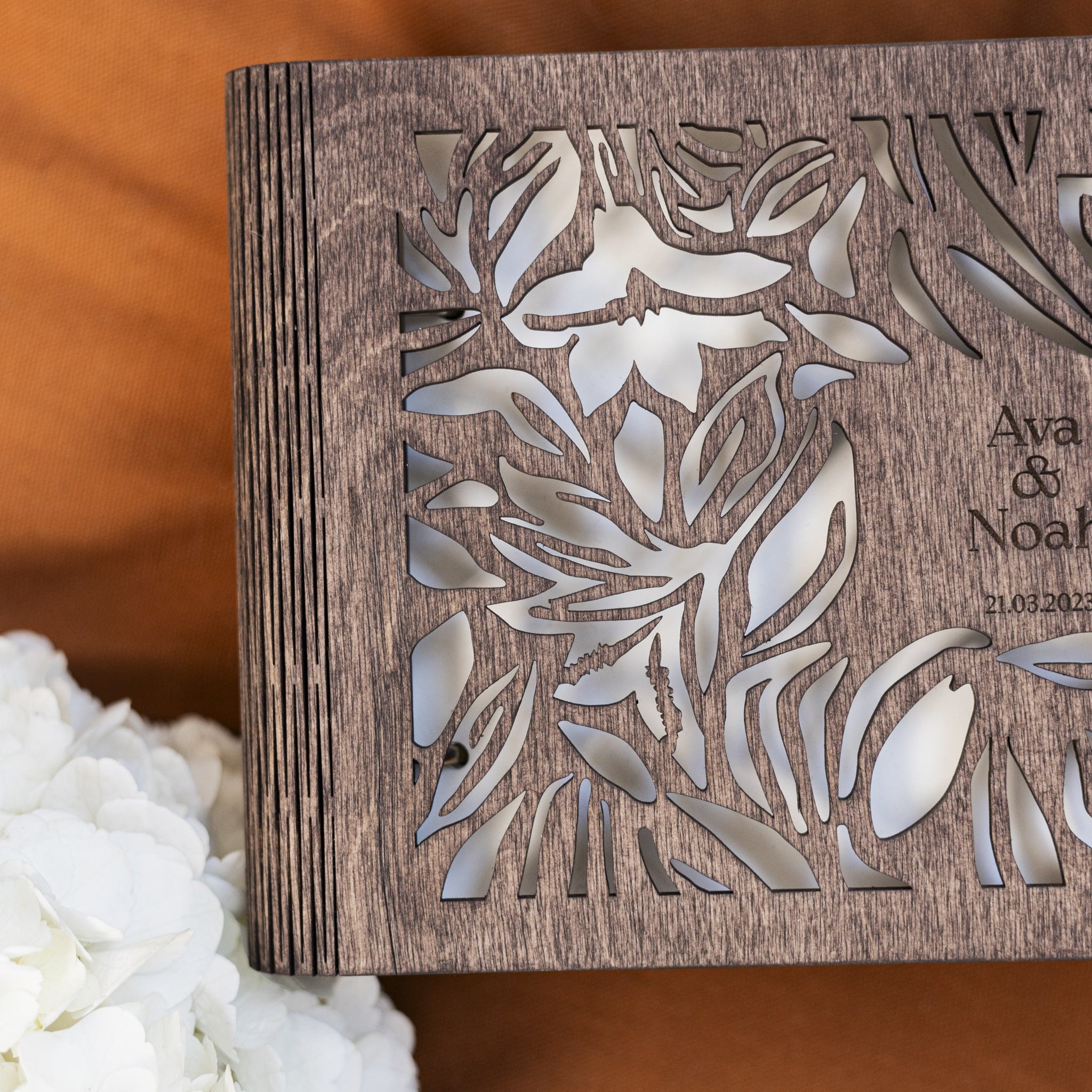 Wooden box with floral cutout design and engraved text on a wooden surface.