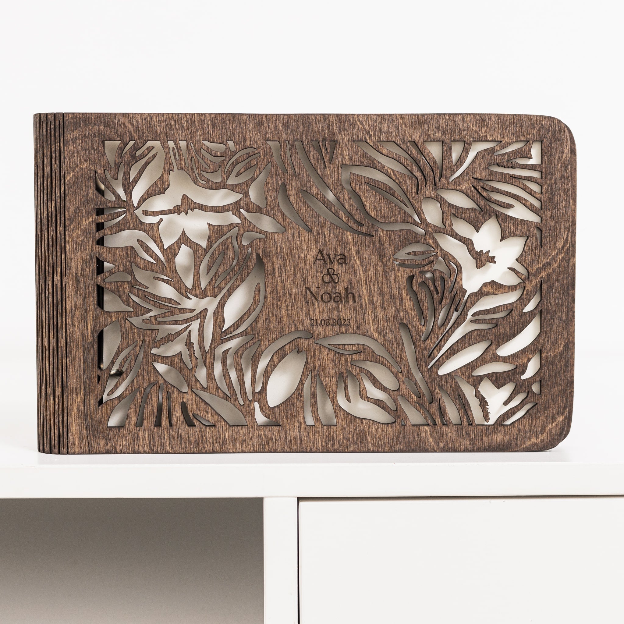Wooden box with floral cutout design and 'Ava & Noah' engraving on a white background