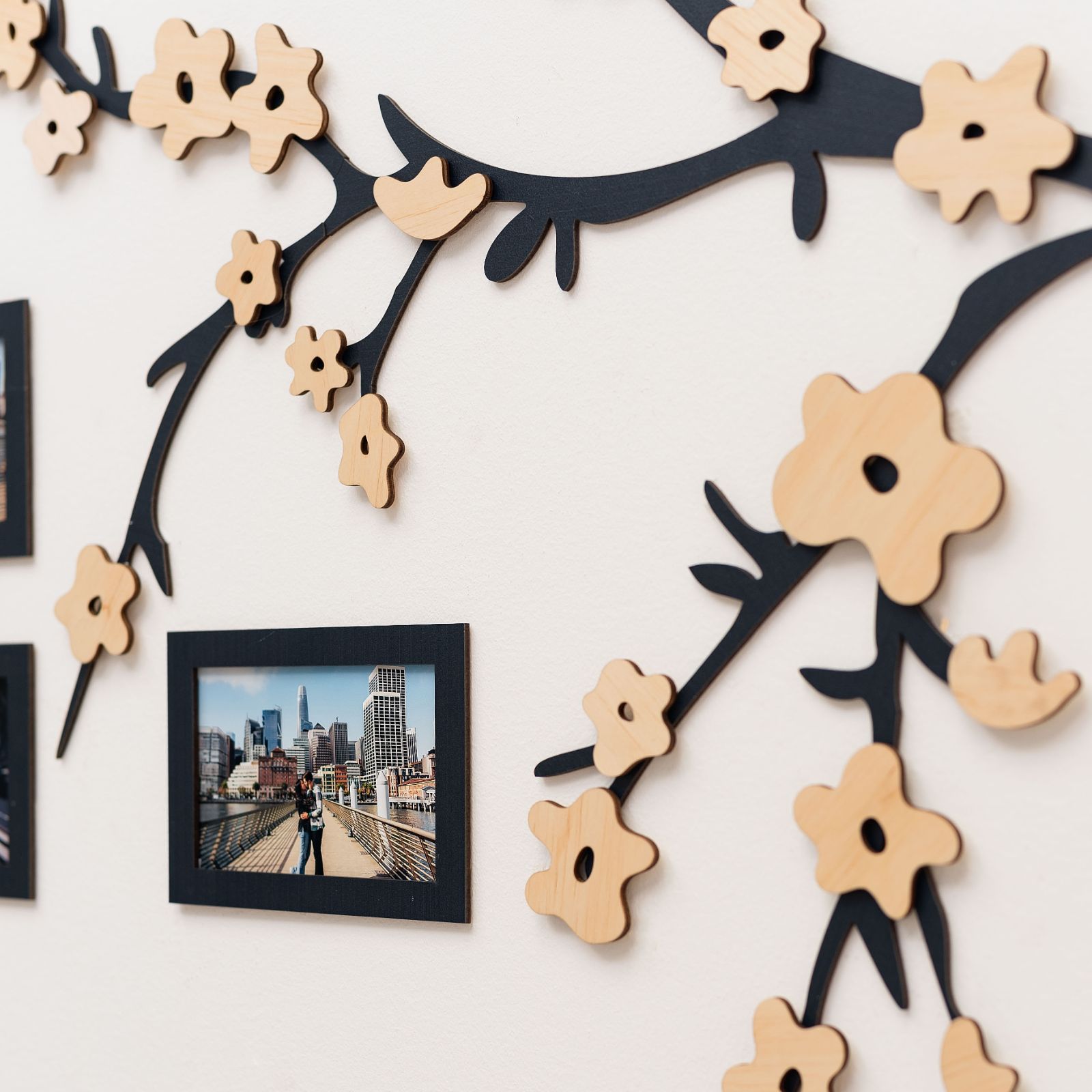 Wooden wall photo frame with decorative black branches and natural wood flowers.
