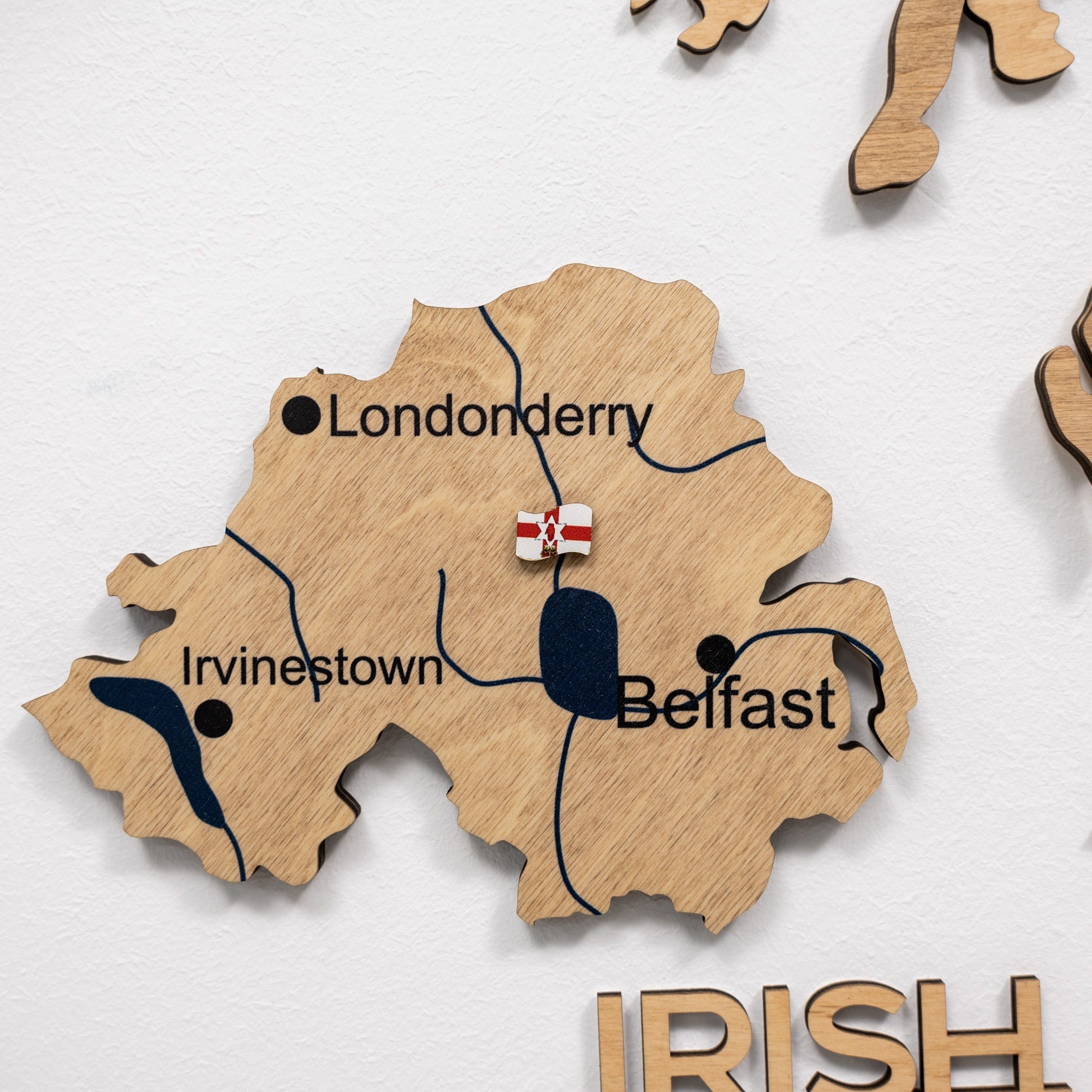 Wooden map of Ireland with Belfast, Londonderry, and Inverness labeled on a white background.