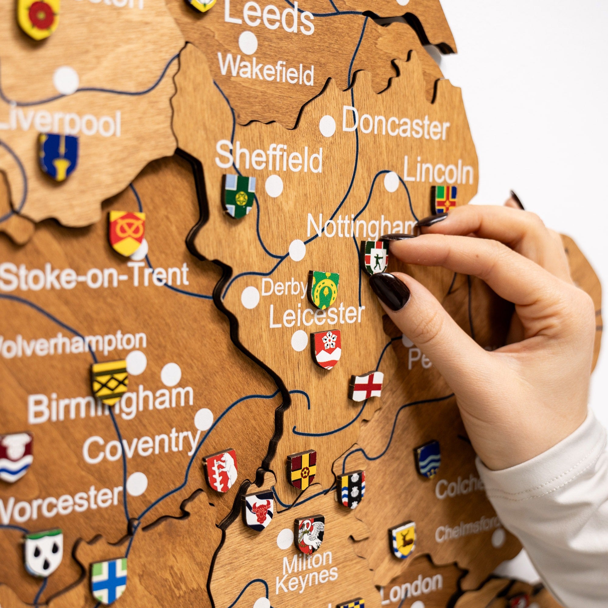 Wooden map of England with city pins and a hand interacting with it
