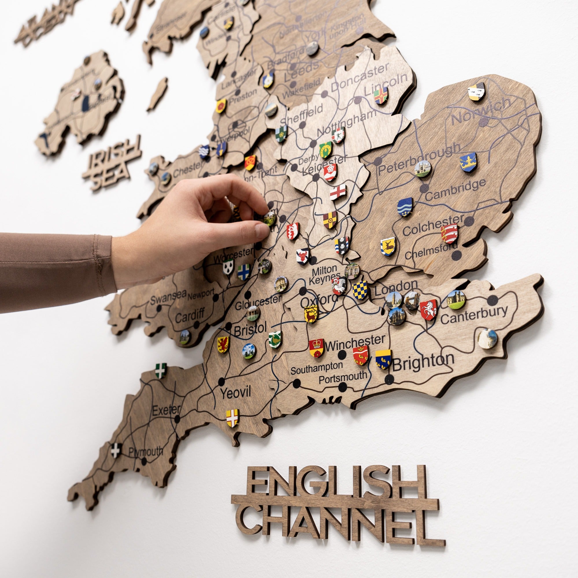 Wooden map of England with pins and a hand interacting with it