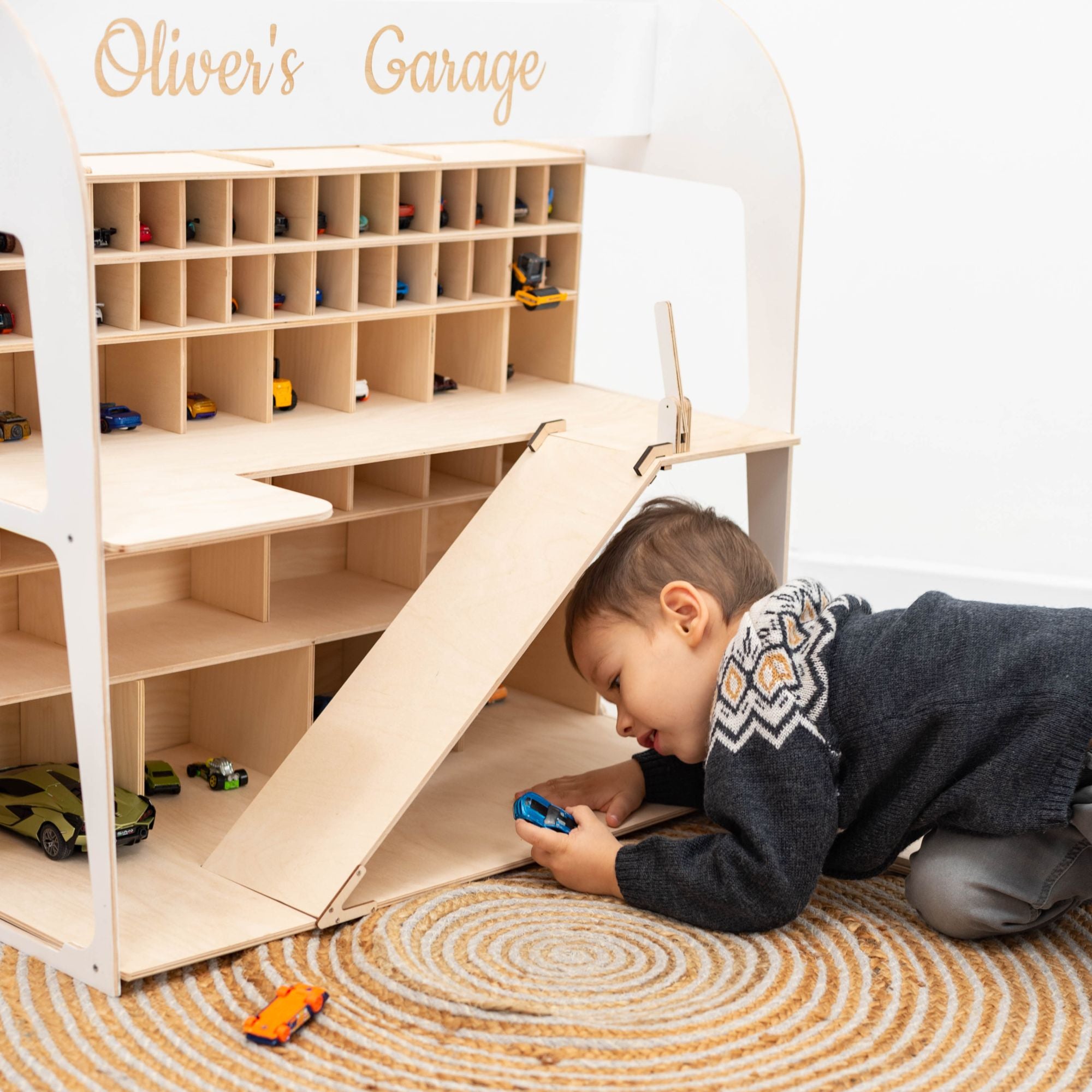 Kid playing with cars on wooden garage organizer