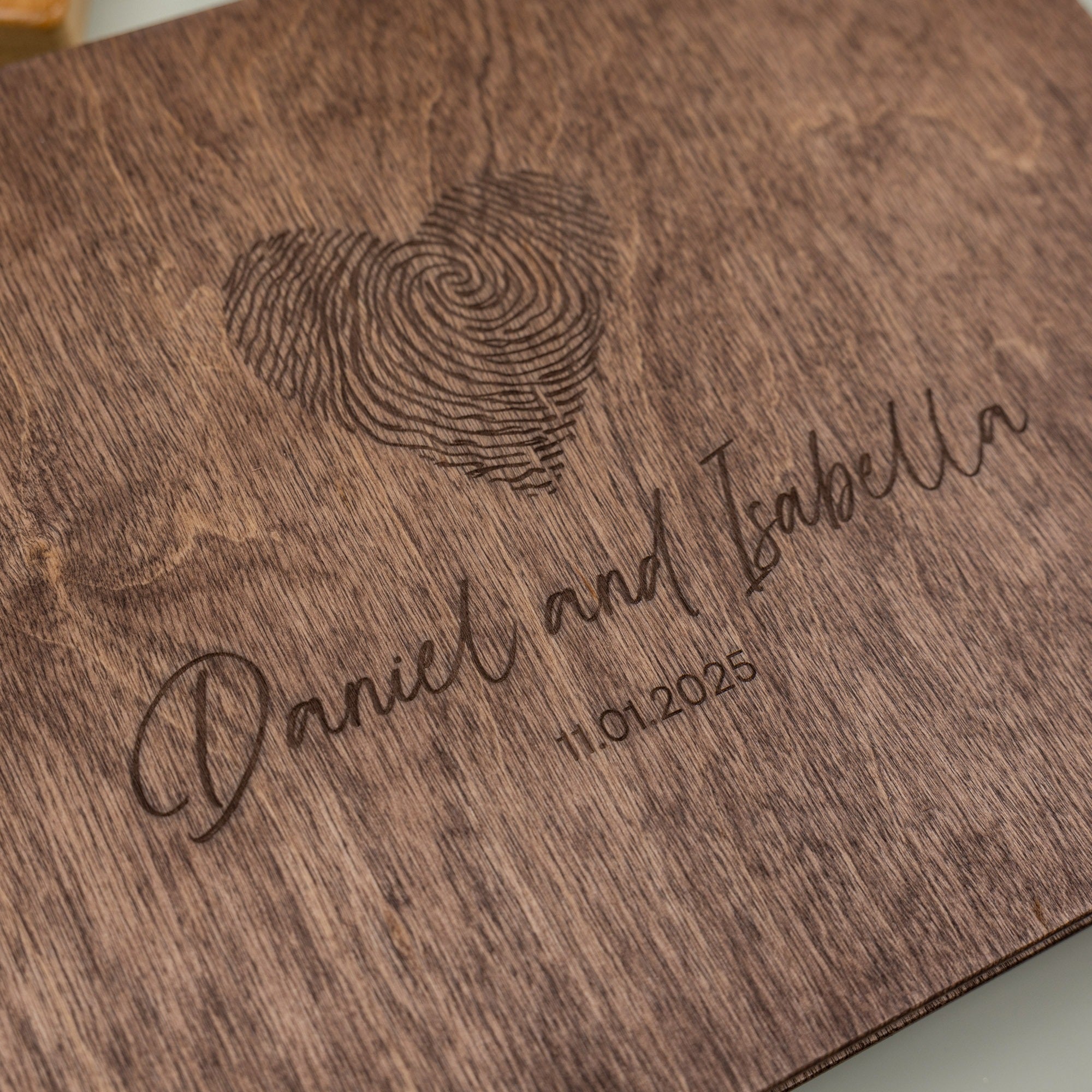 Wooden plaque with engraved fingerprint and names 'Daniel and Isabella' along with a date.